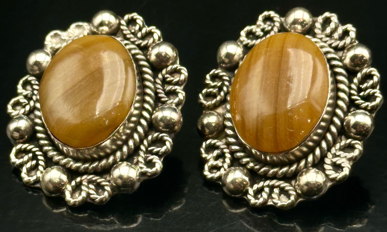 Sterling Silver Golden Tiger’s Eye Oval Earrings, Rope & Bead Design, 26g: Vintage sterling silver earrings featuring rich golden-brown tiger’s eye cabochon stones framed in ornate rope twist and beaded silverwork. The stones display natural chatoyancy with warm banded glo