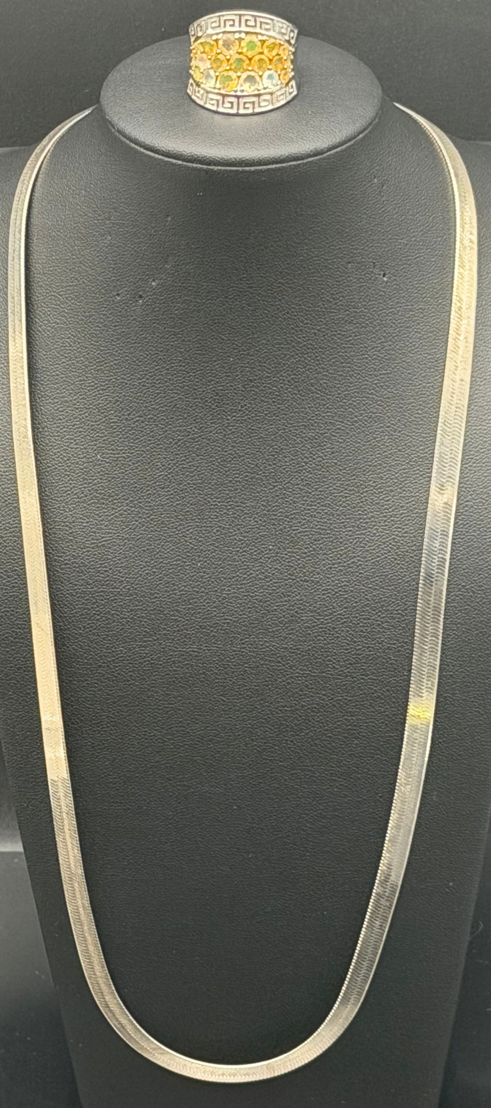 flat Italian herringbone necklace and a bold wide-band statement ring. Necklace clasp is stamped 925: flat Italian herringbone necklace and a bold wide-band statement ring. Necklace clasp is stamped 925 Italy. The ring has a Greek key border design with yellow-green accent stones across the center.