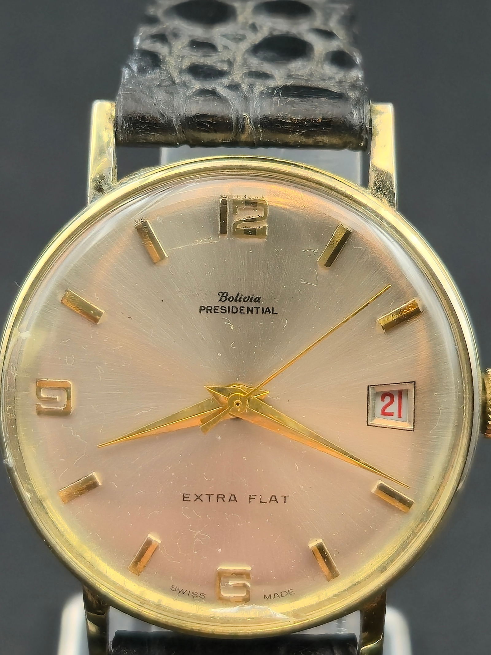 Bolivia Presidential Extra Flat Swiss Electronically Timed Wristwatch Gold Tone 33mm: Vintage Bolivia wristwatch featuring a signed Presidential dial. The silver-tone dial is marked Bolivia Presidential with Extra Flat above 6 o’clock. Caseback is stamped Electronically Timed, Stainl