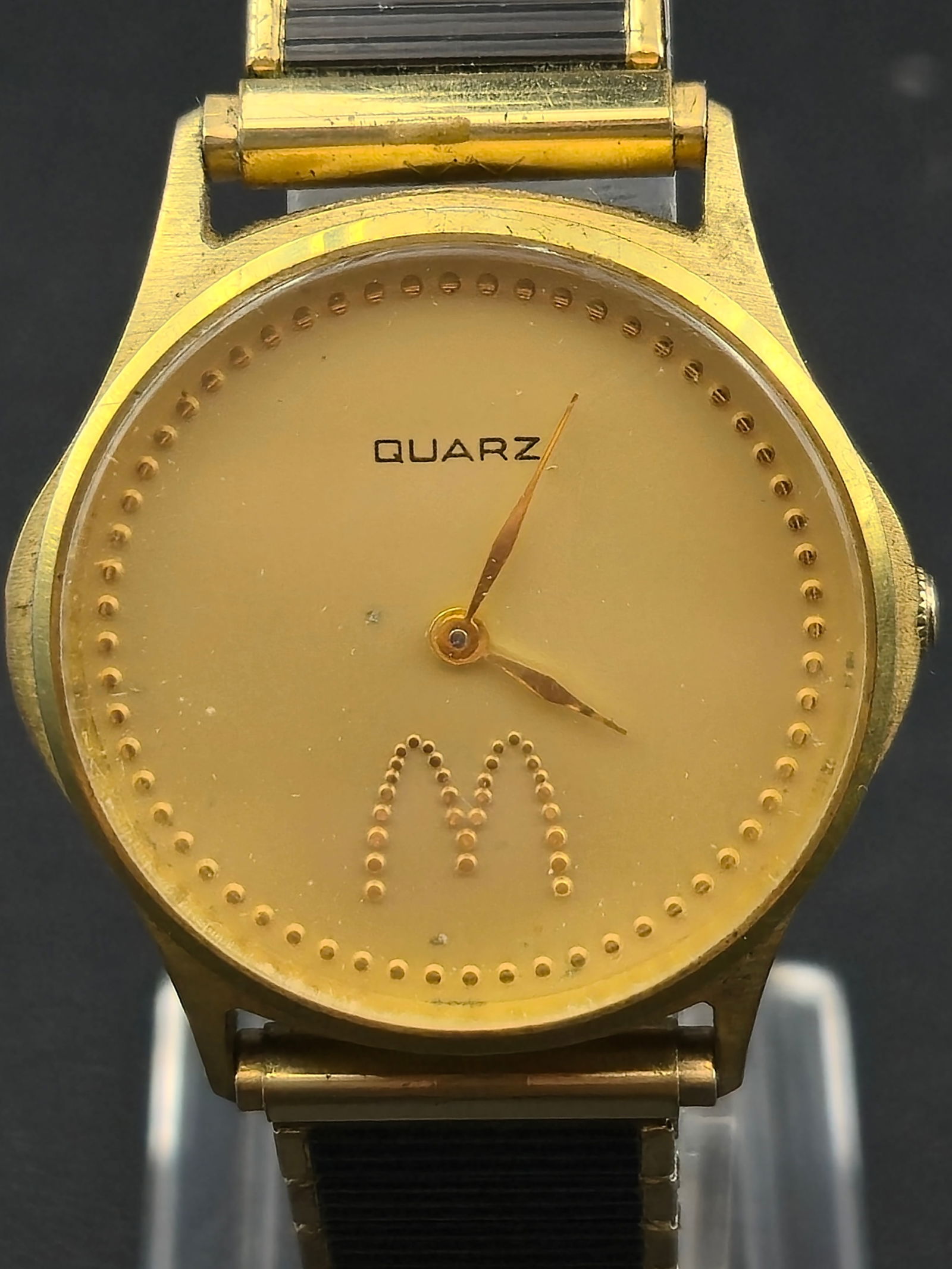 1990s McDonalds Quartz 32mm Gold Tone Dial Watch Stainless Back: Vintage McDonald’s–branded quartz wristwatch featuring a minimalist gold dial with applied dotted hour markers and a raised “M” logo at 6 o’clock. The dial is signed Quartz only, with no