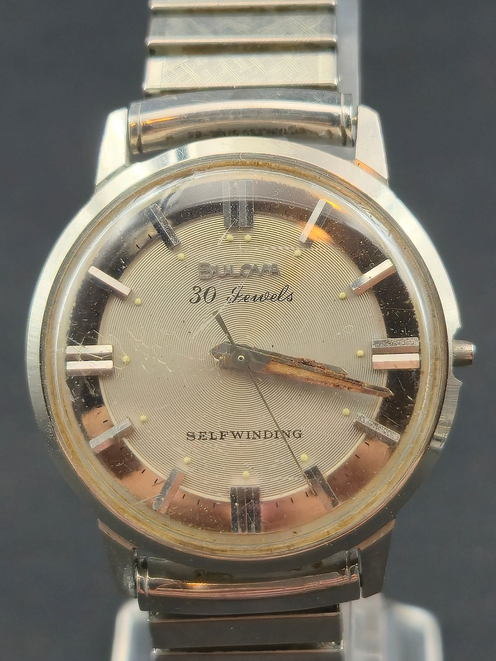 1954 Bulova 30 Jewels Self Winding Stainless Steel 34mm Watch: Vintage Bulova self-winding wristwatch featuring a silver dial marked “Bulova 30 Jewels” with “Self Winding” text and applied baton hour markers. The watch is housed in a stainless ste