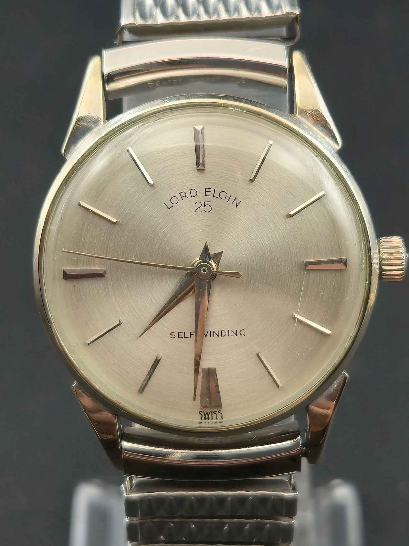1960s Lord Elgin 25J Self-Winding 10K White Gold Filled 25mm Runs: Vintage Elgin Lord Elgin automatic wristwatch featuring a refined silver sunburst dial with applied baton markers and sharp dauphine hands. The dial is signed “Lord Elgin 25” and “Self Windi