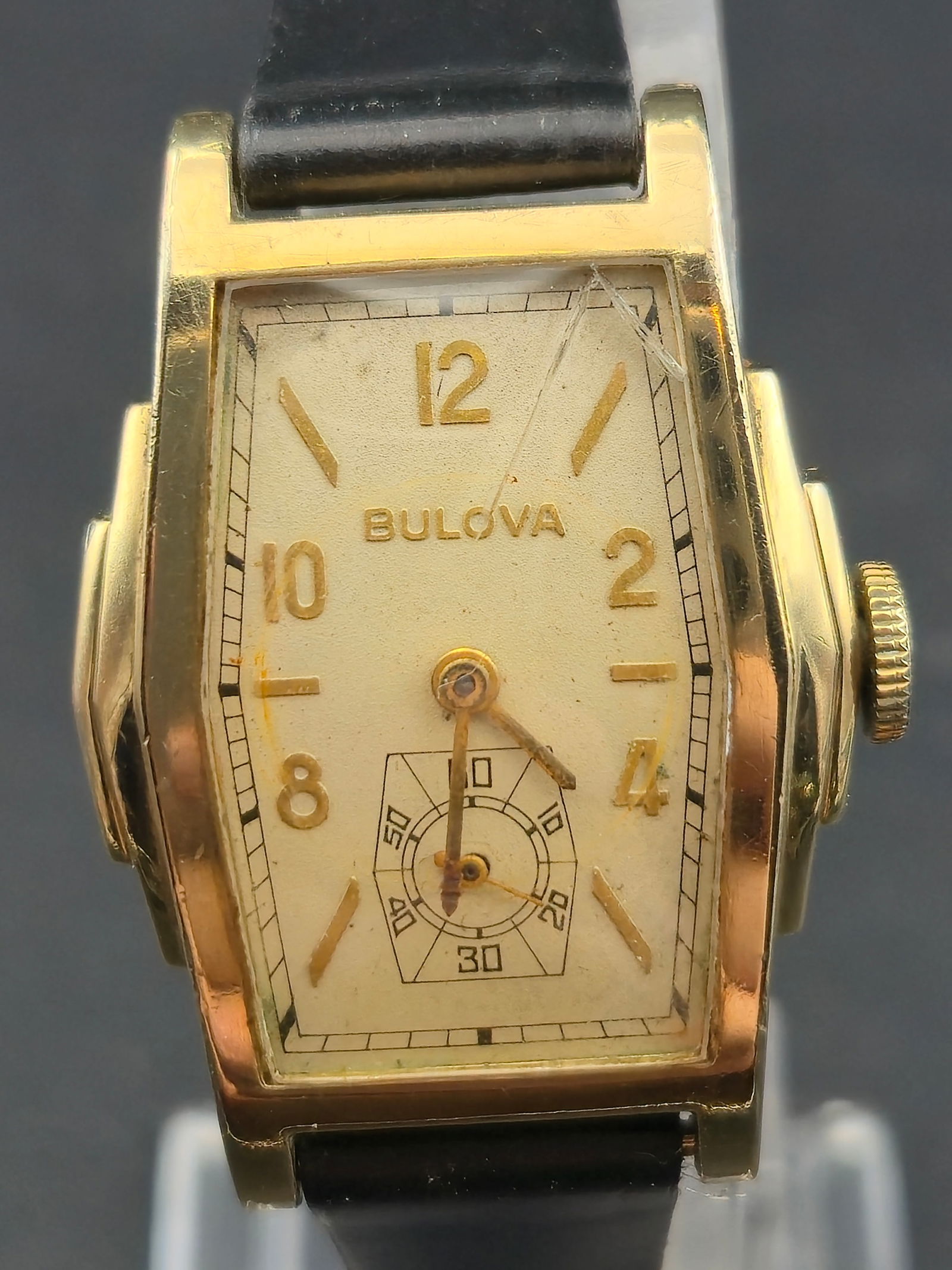 1950s Bulova Rectangular 17J Manual Wind 10K RGP Wristwatch: Vintage Bulova rectangular wristwatch with original silver-tone dial signed Bulova, applied Arabic numerals, and subsidiary seconds at 6 o’clock. Gold-tone rectangular case with stepped sides and pe
