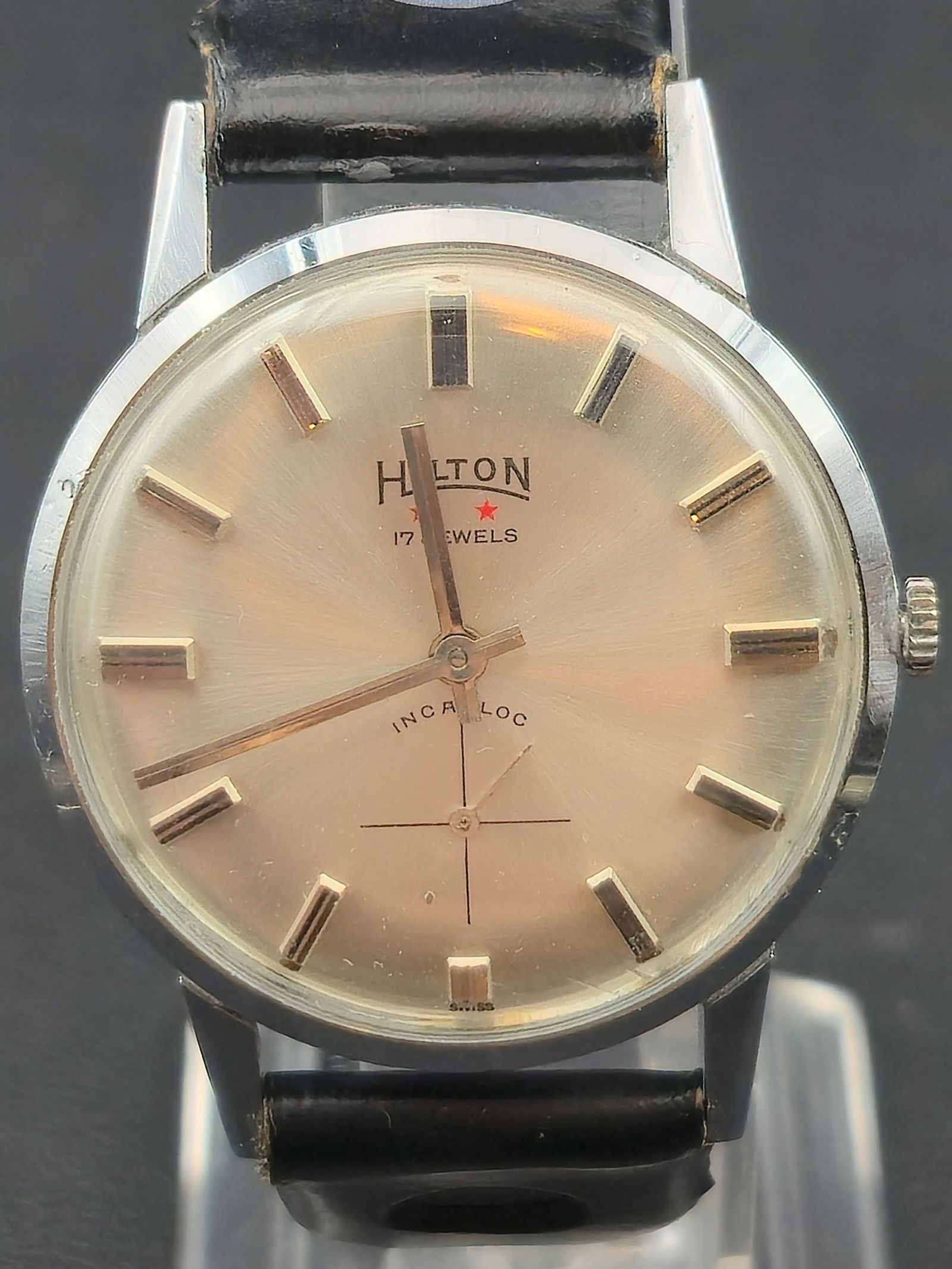 Hilton Swiss 17 Jewel Incabloc Manual Wind Wristwatch c. 1950s: Vintage Swiss-made Hilton wristwatch featuring a champagne sunburst dial with applied baton hour markers and red star logo beneath the brand name. Dial is signed 17 Jewels and Incabloc, indicating a s