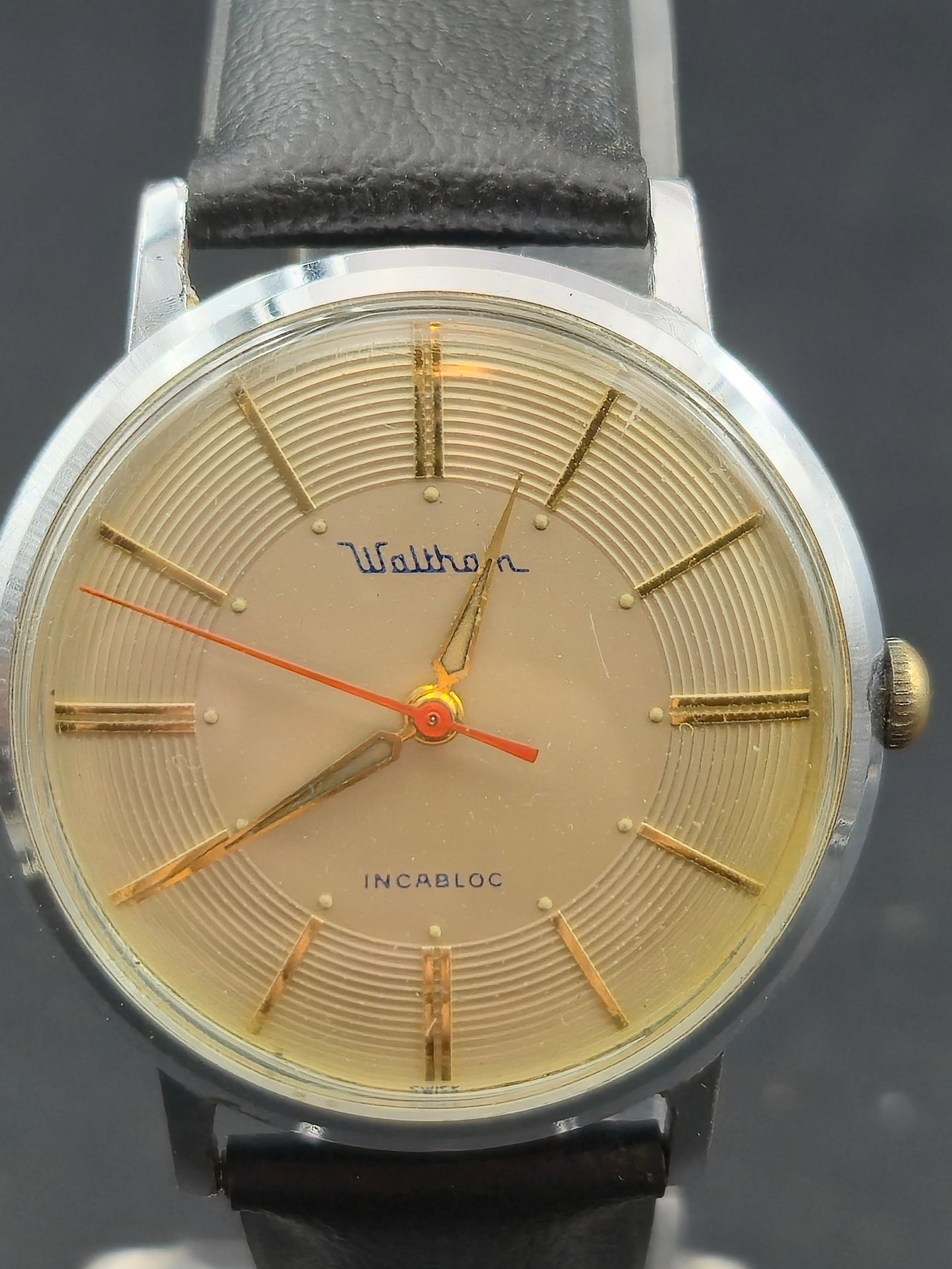 1950s Waltham Swiss Incabloc 17J Manual Watch 34mm Stainless Steel Running: Vintage Waltham Swiss-made wristwatch featuring a champagne-tone textured dial with applied gold baton hour markers and a red sweep seconds hand. Dial signed Waltham and Incabloc. Powered by a Swiss 1