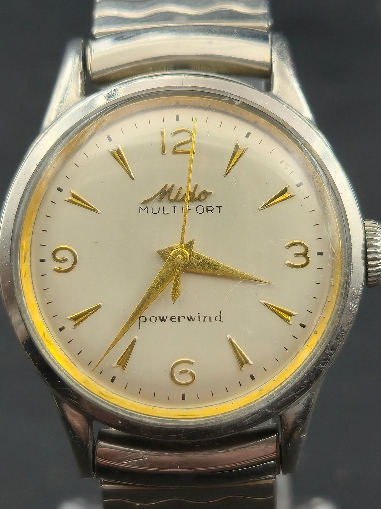 1960s Mido Multifort Powerwind 0917P 30mm Stainless Steel Swiss Automatic Watch: Vintage 1960s Mido Multifort Powerwind automatic wristwatch featuring a silver dial with applied gold tone arrow markers and Arabic numerals at 12, 3, 6, and 9. Dial marked “Mido Multifort” an