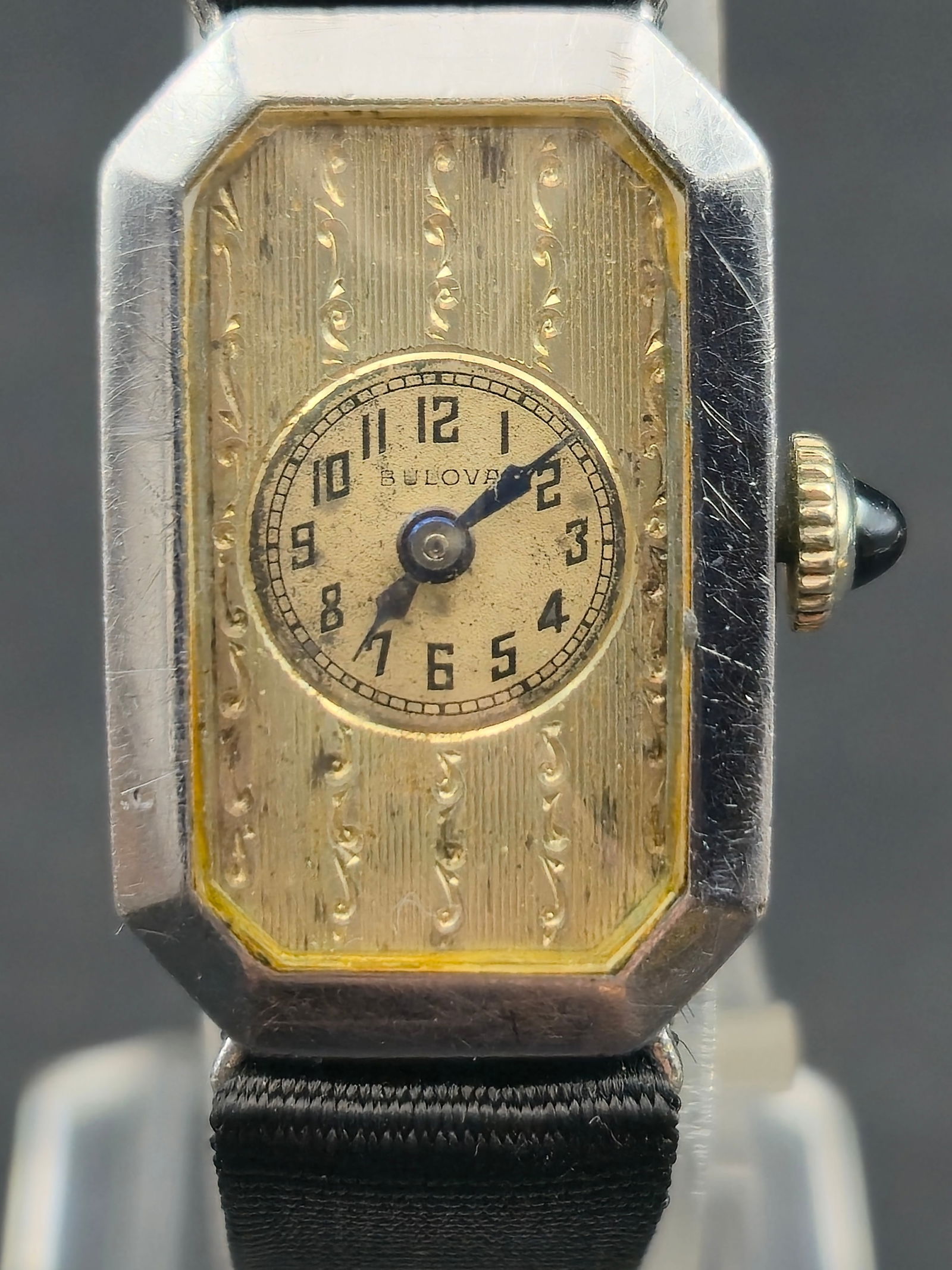 1930s Bulova 14K White Gold Filled Ladies Art Deco 15J 17mm: Vintage Bulova ladies Art Deco wristwatch with rectangular case and engraved bezel details. Silver tone dial with Arabic numerals and blued hands. Crown set with blue cabochon. Case interior marked Bu