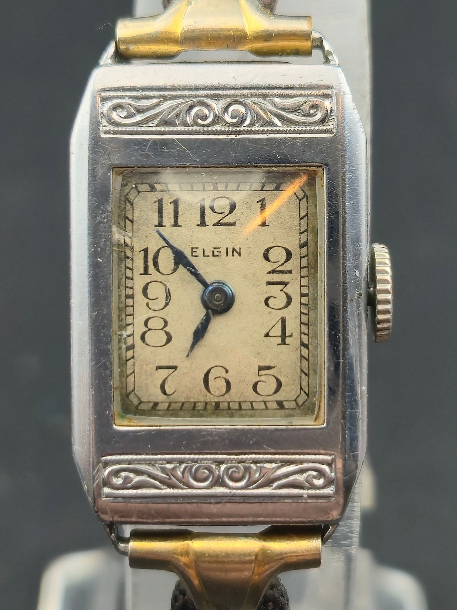 1928 Elgin Ladies Art Deco 17mm Nickel Case Cal 33196447: Vintage Elgin ladies Art Deco wristwatch with engraved rectangular nickel case and decorative top and bottom scrollwork. Cream dial with black Arabic numerals and blued hands. Dial signed Elgin. Case