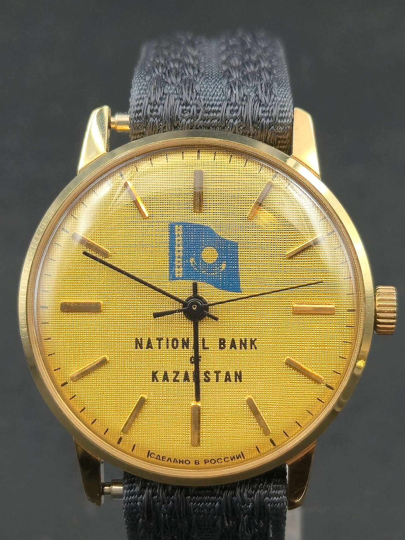 1970s USSR National Bank Kazakhstan Dial 34mm Gold Tone Mechanical: Vintage mechanical wristwatch featuring gold tone textured dial marked National Bank Kazakhstan with flag emblem. Lower dial text in Cyrillic reads Made in Russia. Applied gold tone baton hour markers