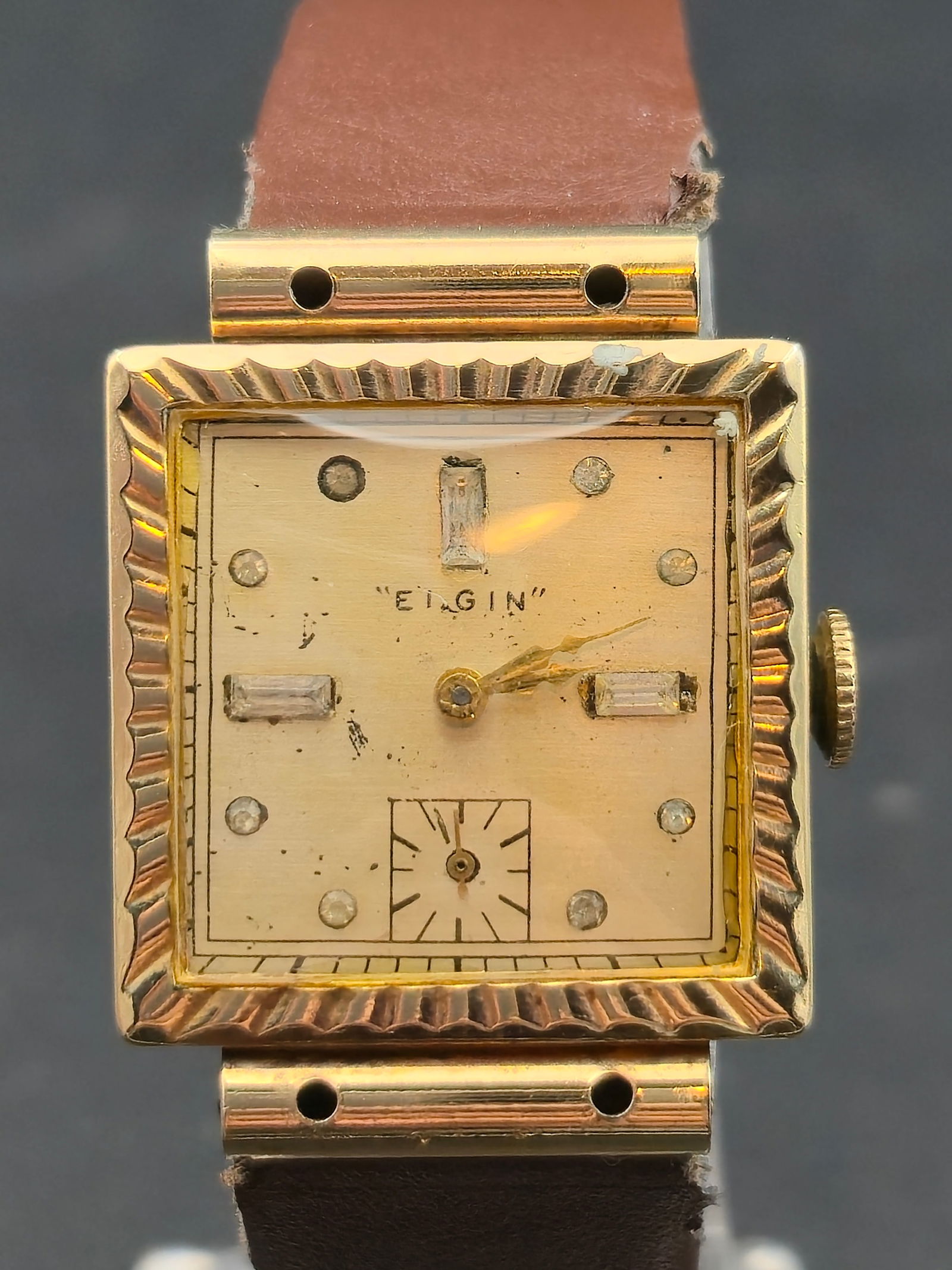 1951 Elgin 7J 25mm Square Gold Filled Case Small Seconds Runs: featuring gold filled case with stepped fluted bezel design. Cream dial marked Elgin with applied faceted hour markers including baguette style at 12 3 and 9. Small seconds subdial at 6.Manual wind mo