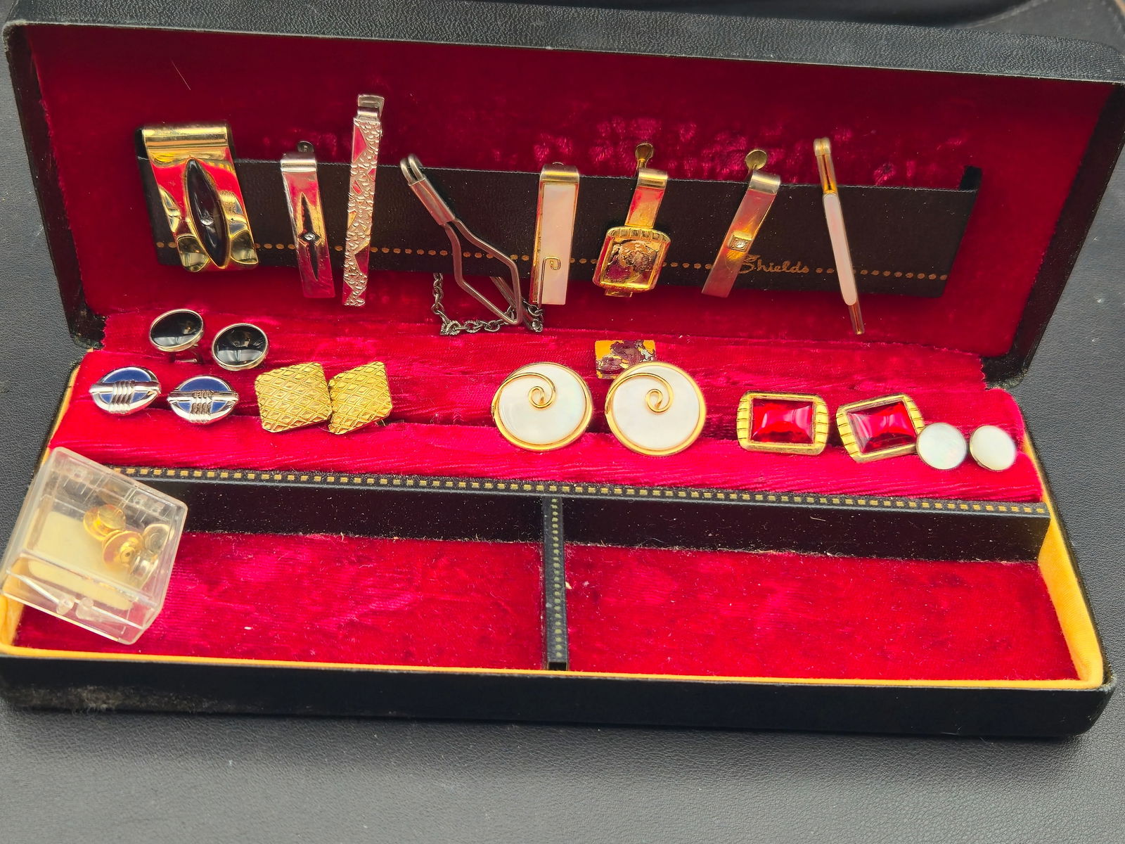 Vintage Cufflink & Tie Clip Set Red Glass MOP Enamel in Shields Case: Vintage men’s cufflink and tie clip assortment presented in original red velvet fitted case with Shields branded insert. Includes multiple cufflink pairs in gold-tone and silver-tone finishes featur