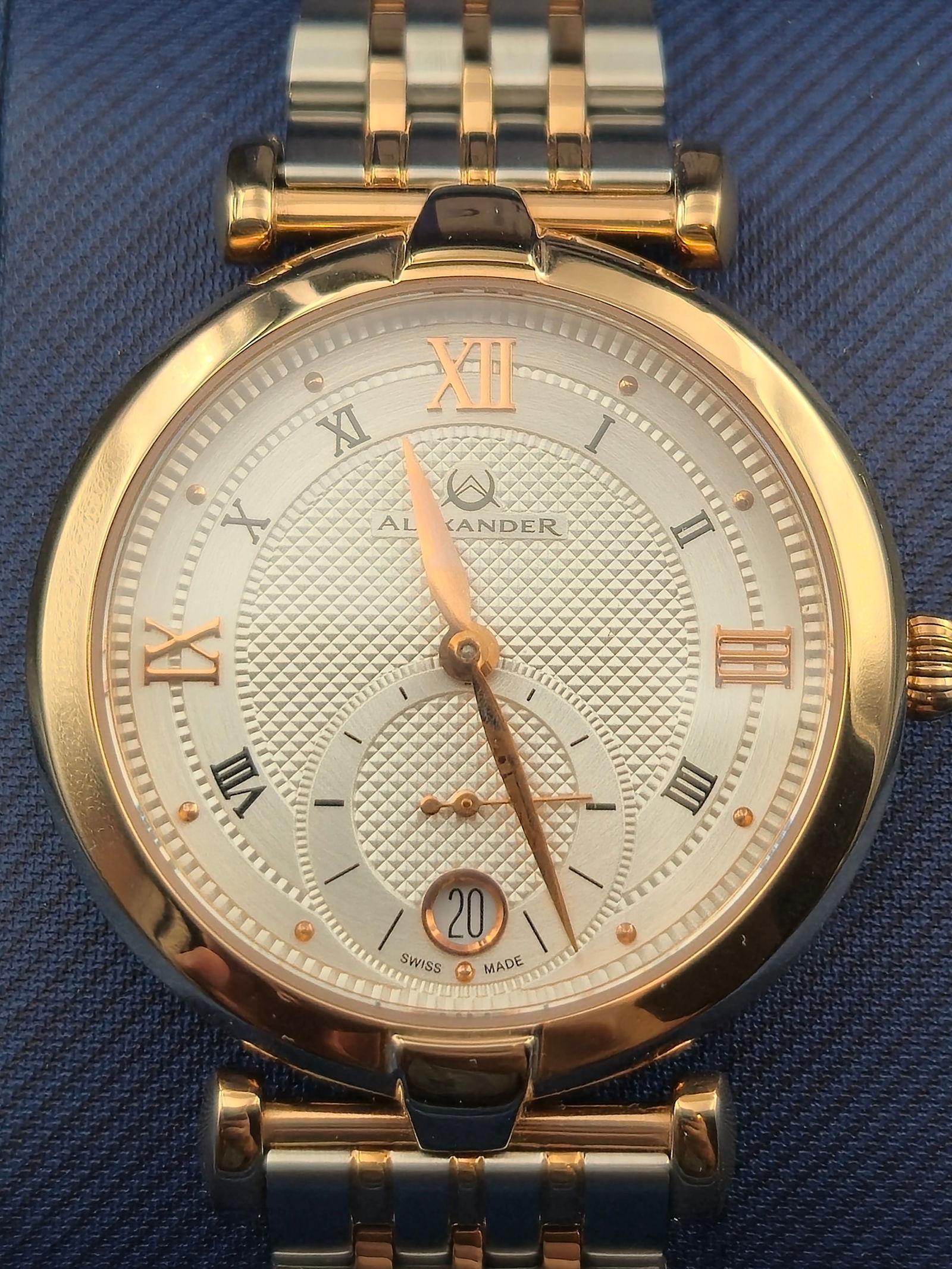 Alexander Swiss Made Quartz Watch 35mm Two Tone Stainless Steel Sapphire Crystal Box: Alexander Swiss made quartz wristwatch with original Alexander presentation box, warranty card, and booklet. The watch features a silver textured dial with applied Roman numeral hour markers, rose gol