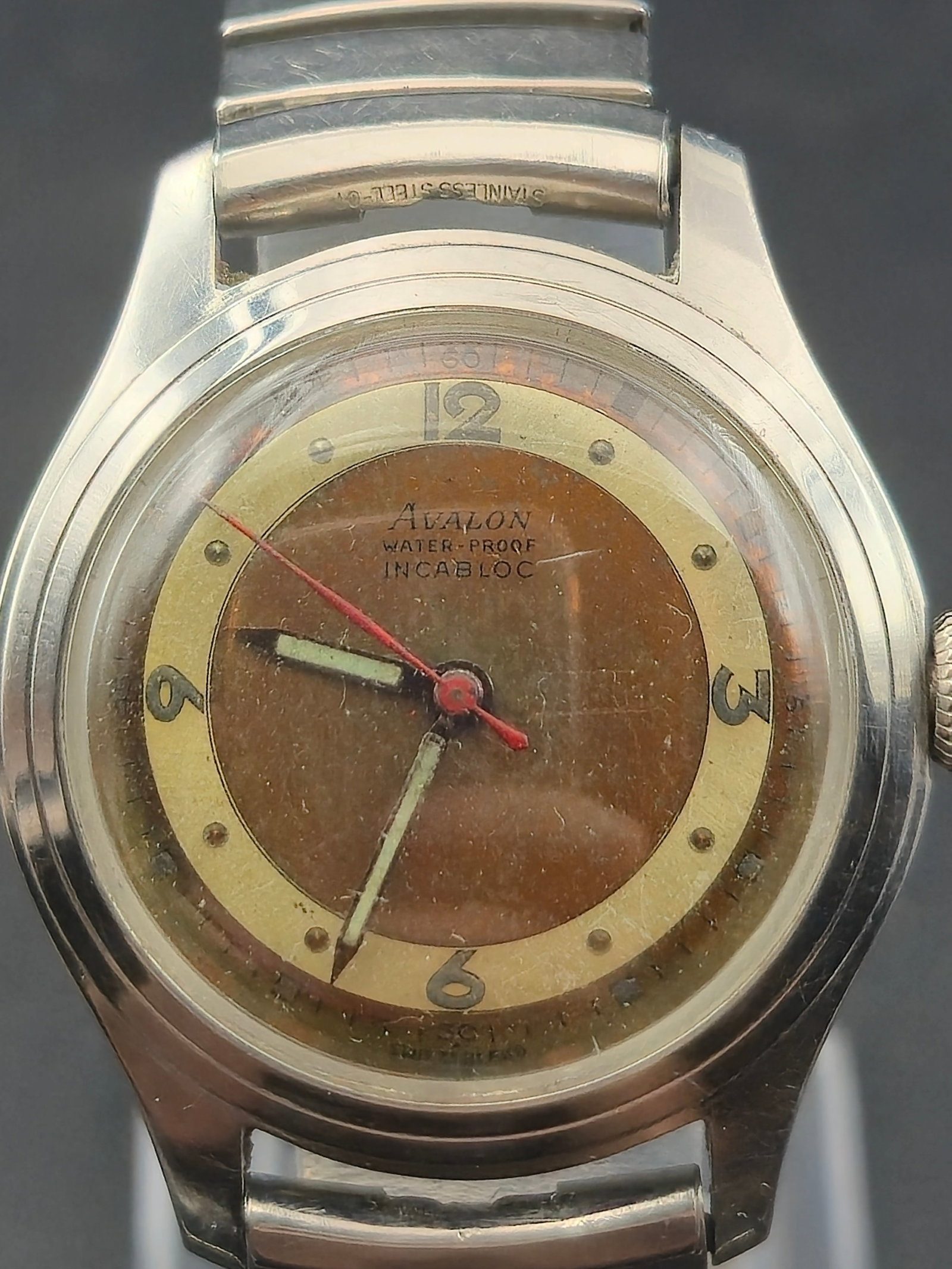 Avalon Water Proof Incabloc 17 Jewel Swiss Mechanical Watch Brown Dial Stainless Steel 1960s Running: Vintage Avalon wristwatch featuring a distinctive two-tone brown and gold dial with Arabic numerals and red sweep seconds hand. The dial is signed “Avalon Water-Proof Incabloc,” indicating the