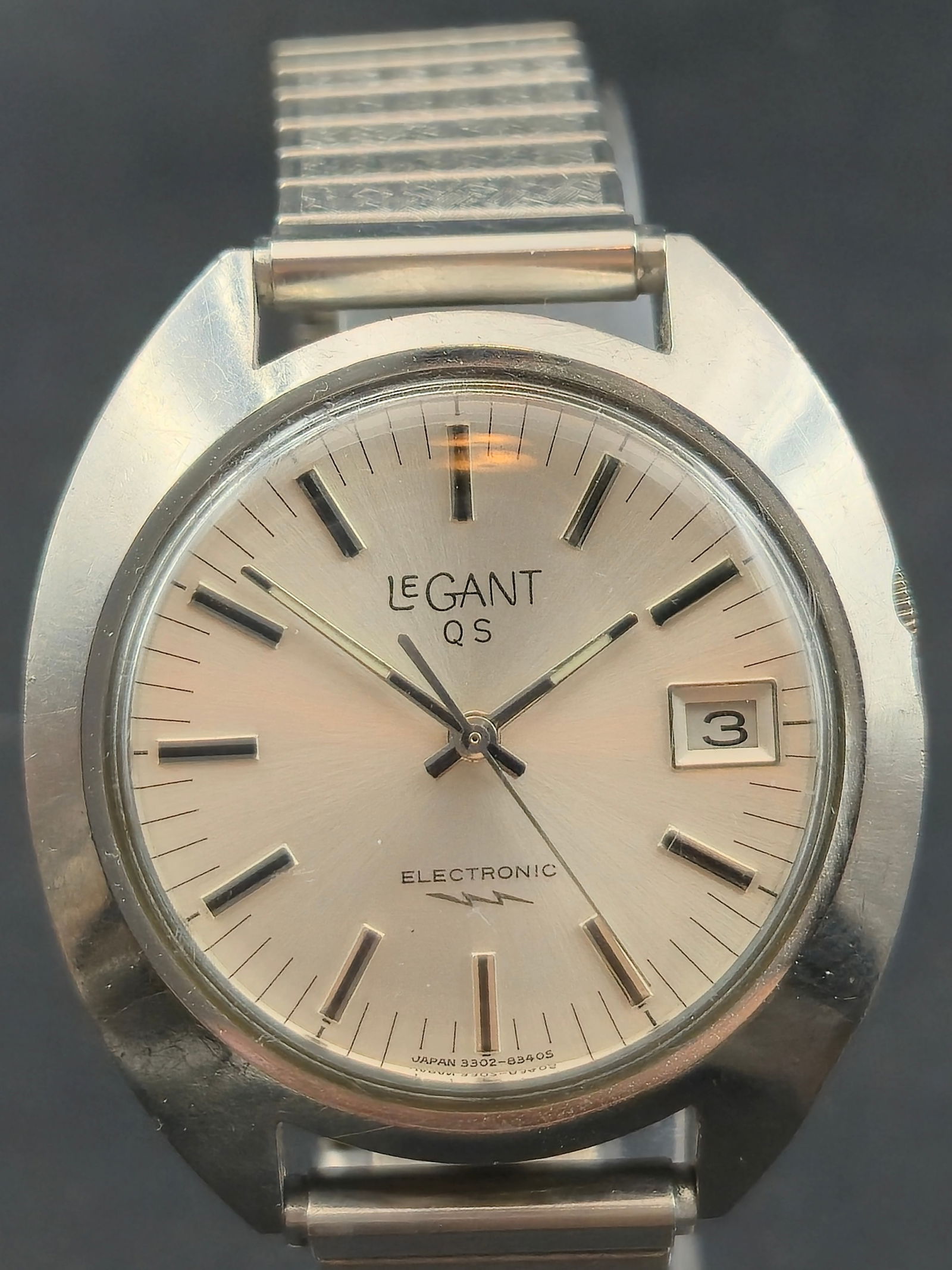 1970s Legant QS Electronic Date Watch Japan 38mm Stainless Steel Running: Vintage Legant QS electronic wristwatch featuring a silver sunburst dial with applied baton hour markers and date window at the 3 position. The dial is marked Legant QS and Electronic with lightning s
