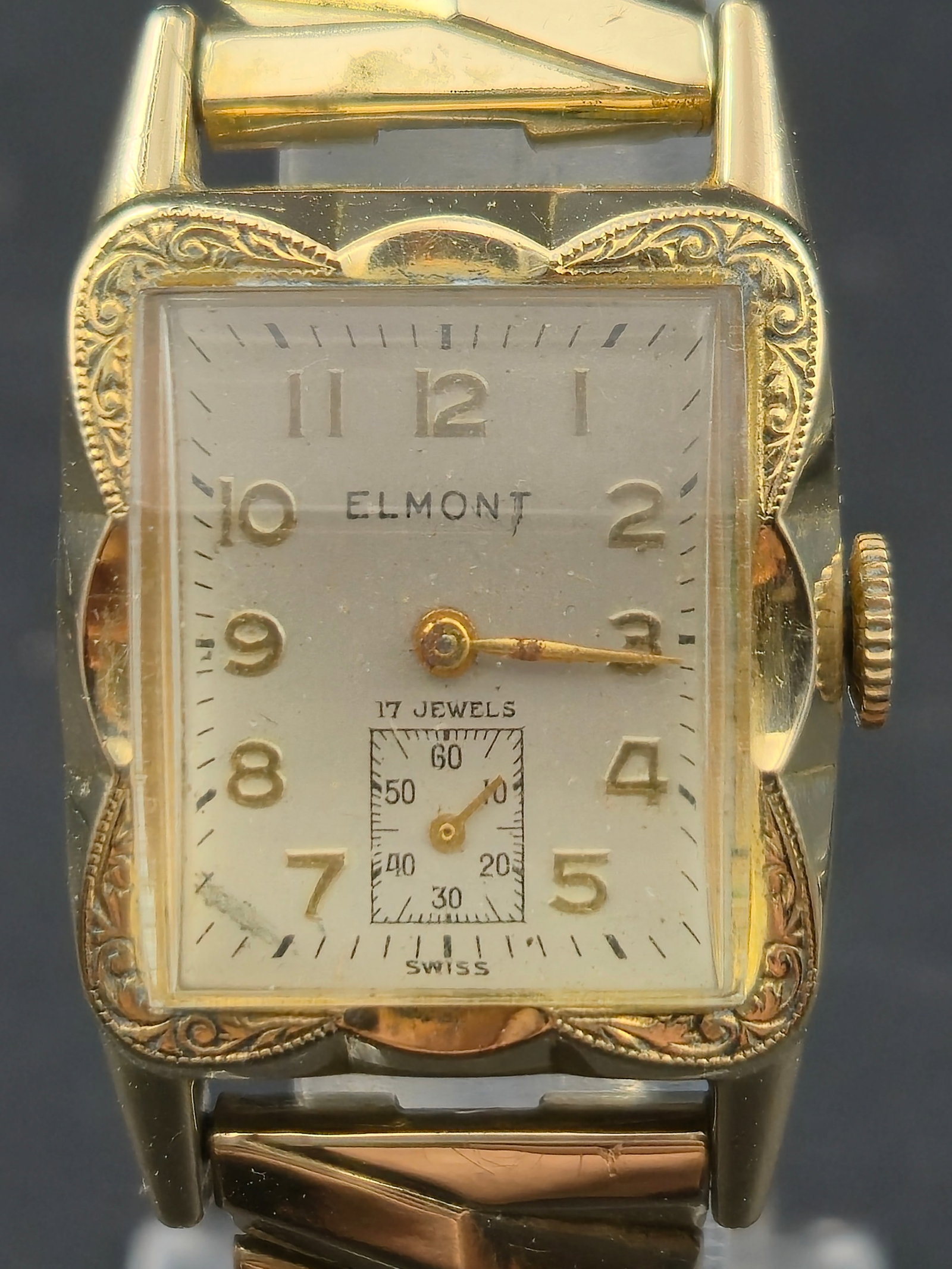 1940s Elmont Art Deco Cushion 10K RGP Bezel 17J Swiss 23mm Sub Seconds Runs Missing Hand: Vintage Elmont Art Deco cushion case wristwatch from the 1940s era. Features an ornate engraved bezel with classic stepped Art Deco design and sub-seconds at 6. Dial marked Elmont, 17 jewels, Swiss, w