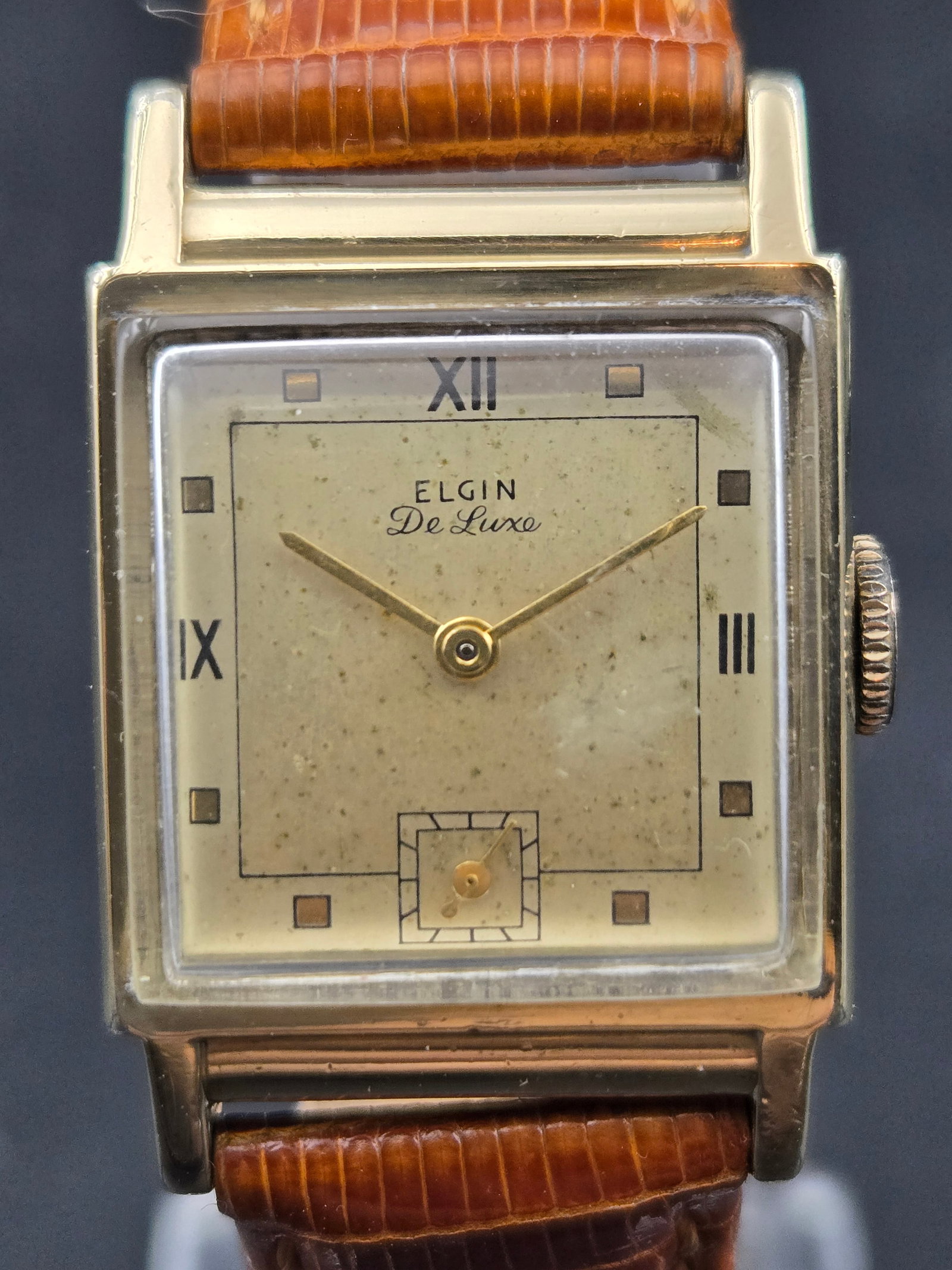 Vintage Elgin DeLuxe Tank 10K Gold Filled 17J Cal 558 Art Deco Sub Seconds 22mm Runs 1940s: Vintage Elgin DeLuxe rectangular tank-style wristwatch featuring a classic Art Deco dial with Roman numerals at 12, 3, and 9, square markers, and a recessed small seconds subdial. Powered by a high-gr