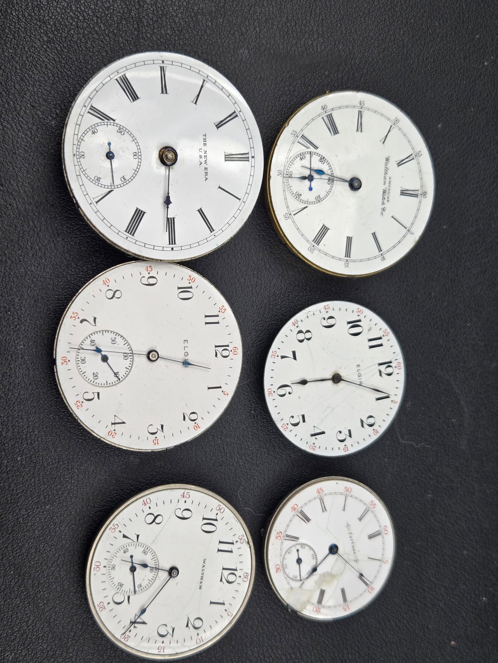 Elgin Waltham The New Era Pocket Watch Parts Lot 15J Movements Dials Some Running: Pocket watch parts lot including identifiable examples from Elgin, American Waltham Watch Co, and The New Era U.S.A.Lot features multiple enamel dials with Roman numerals and sub-seconds, including bo