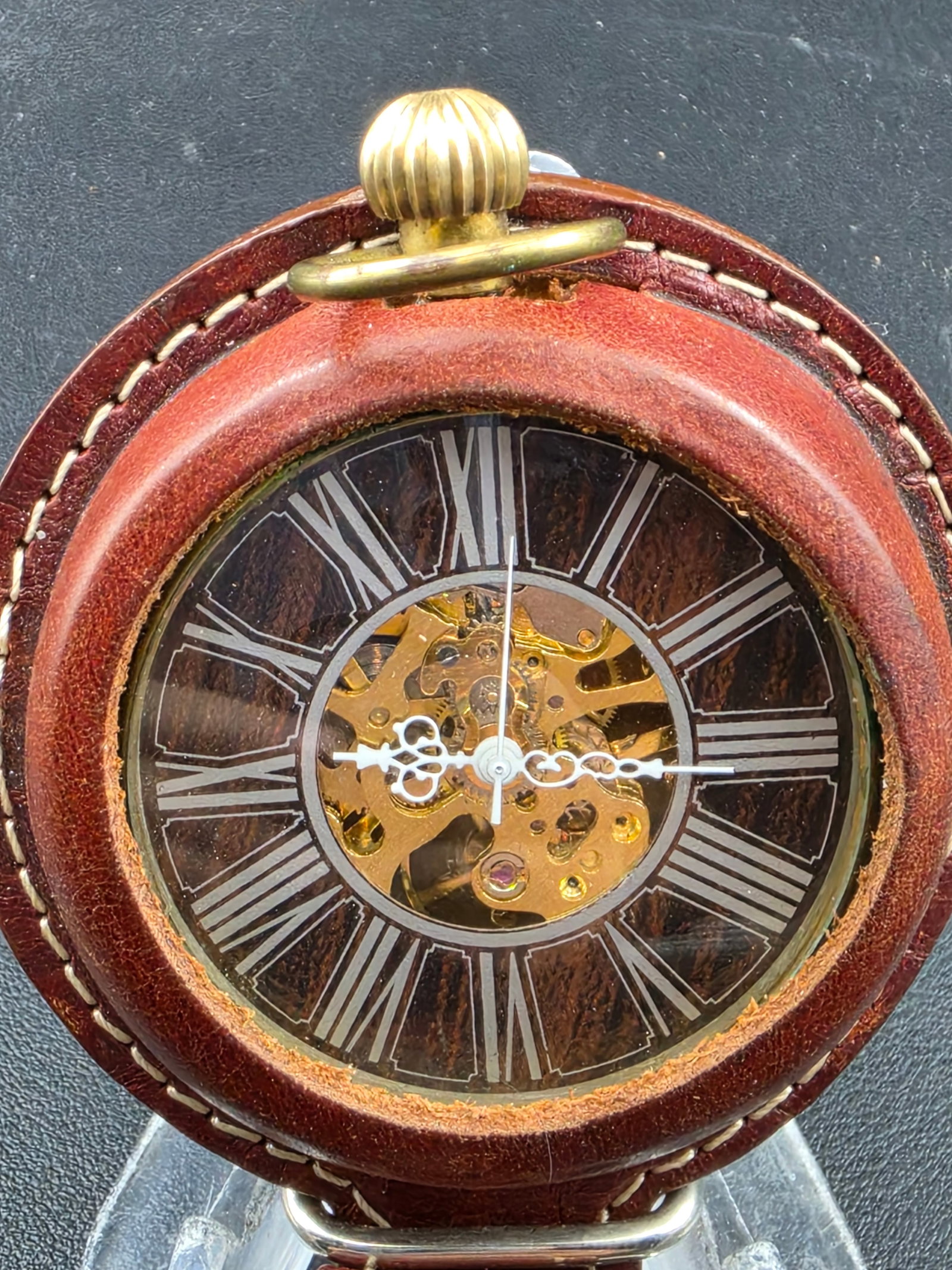 Modern Skeleton Pocket Watch 49 mm Roman Dial Leather Case Runs: Modern skeleton-style pocket watch featuring an open-work dial with Roman numerals and visible mechanical movement. The watch is housed in a gold-tone case and fitted with a leather protective holder.