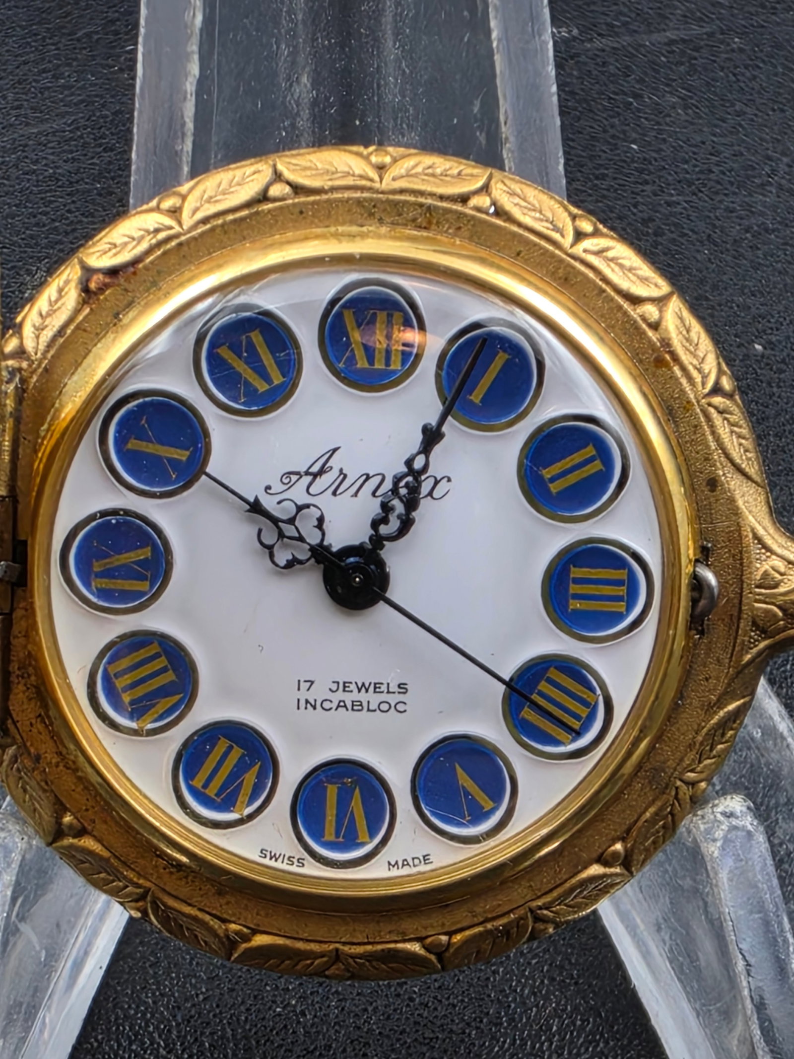 Arnex 17J Incabloc Swiss Pocket Watch Gold Tone 37 mm Enamel Dial Runs: Vintage Arnex Swiss pocket watch featuring a clean white dial with applied blue Roman numeral markers and ornate hands. Marked 17 jewels Incabloc Swiss Made. Housed in a gold-tone case with decorative
