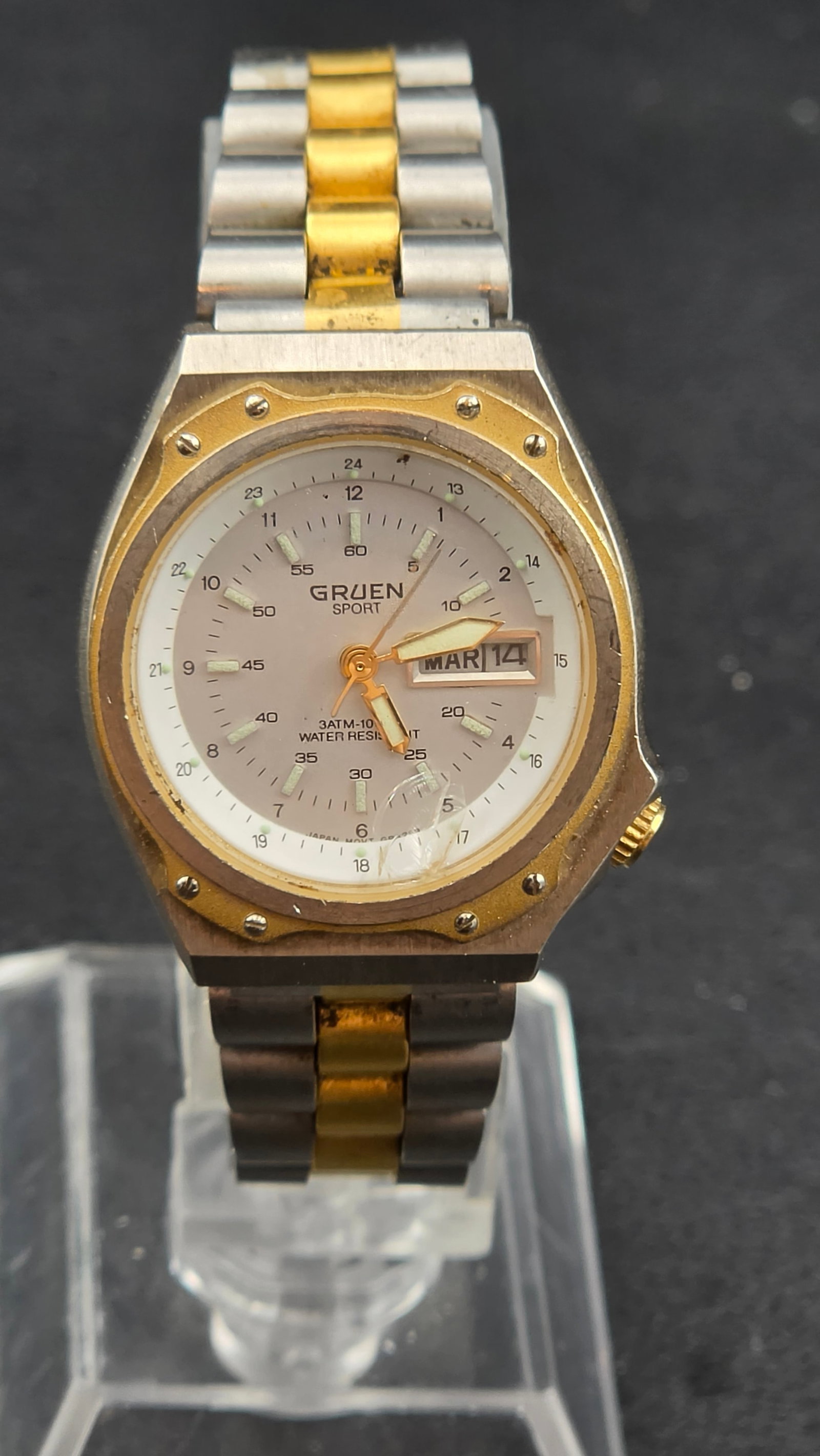Gruen Sport Day Date Quartz Two Tone Watch 26mm 241602 New Battery Running: Vintage Gruen Sport quartz wristwatch featuring a two-tone stainless steel and gold-tone case with decorative bezel screws and integrated bracelet. The dial includes day and date display at 3 o’cloc