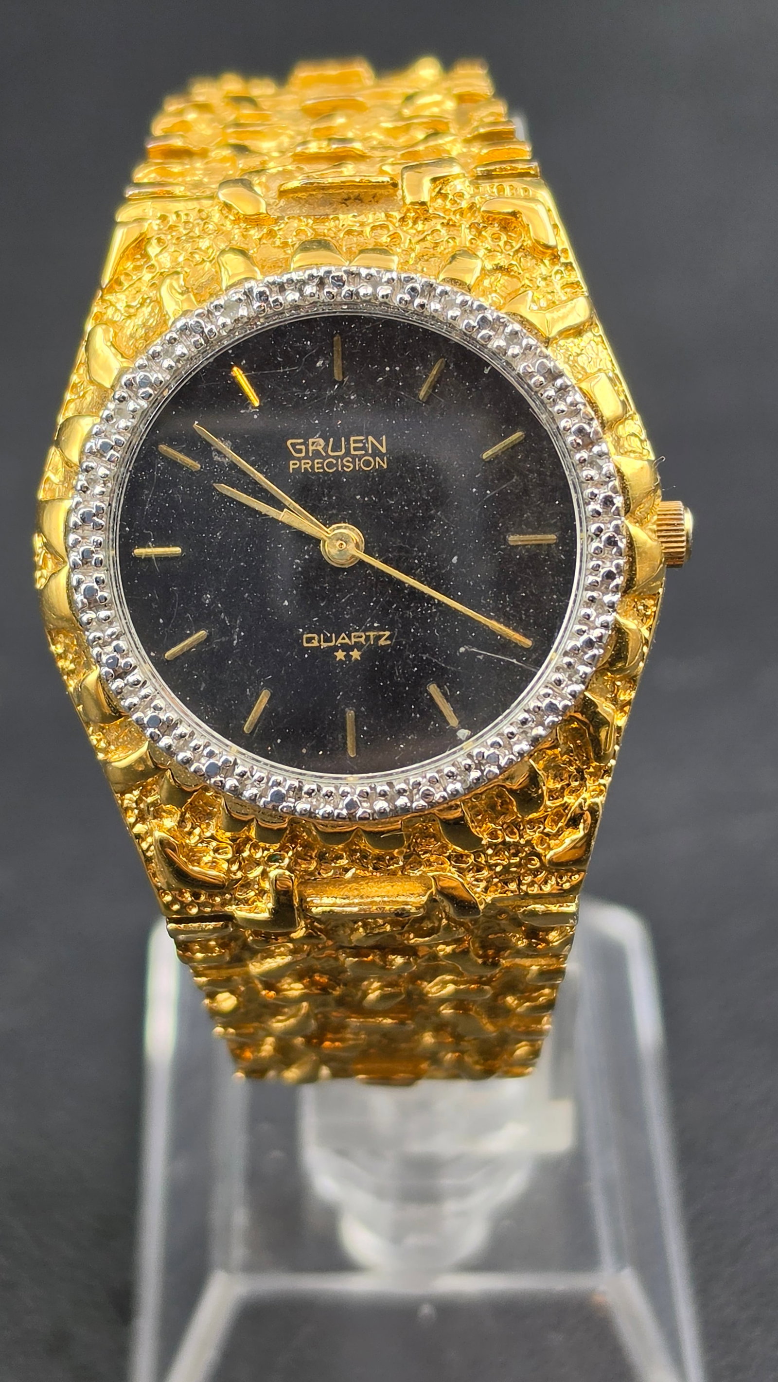 Gruen Precision Quartz Gold Tone Nugget Style Watch 33mm Black Dial Running: Gruen Precision quartz wristwatch featuring a bold gold-tone nugget-style case and bracelet with textured finish. Black dial with gold-tone markers and a stone-set bezel adds a striking vintage look. 