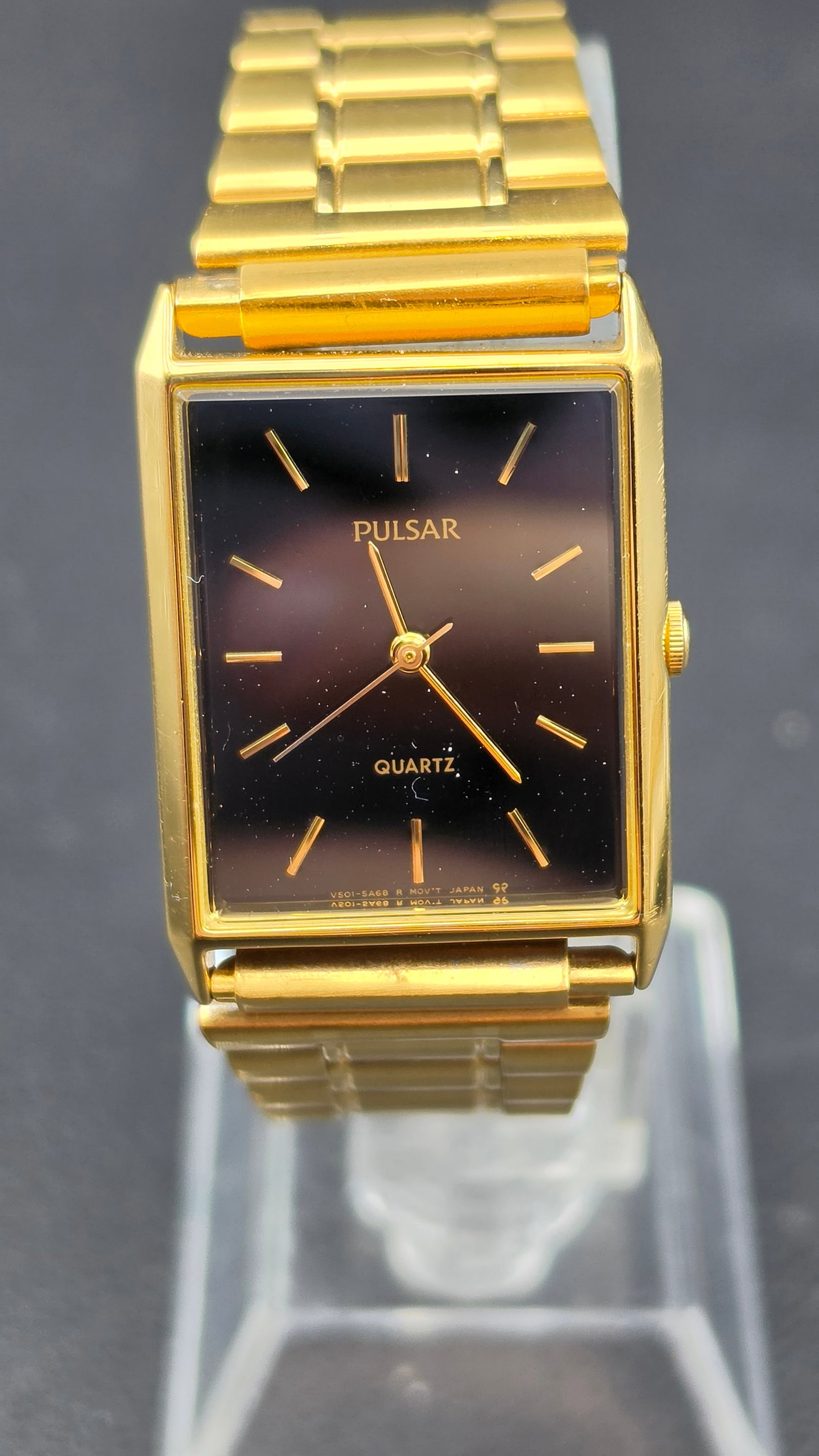 Pulsar Quartz Rectangular Gold Tone Black Dial V501-5A20 Japan Runs New Battery: Pulsar quartz wristwatch featuring a rectangular gold tone case with a black dial and gold stick markers. Clean minimalist design with three-hand layout.Dial marked “Pulsar Quartz.” Caseback m