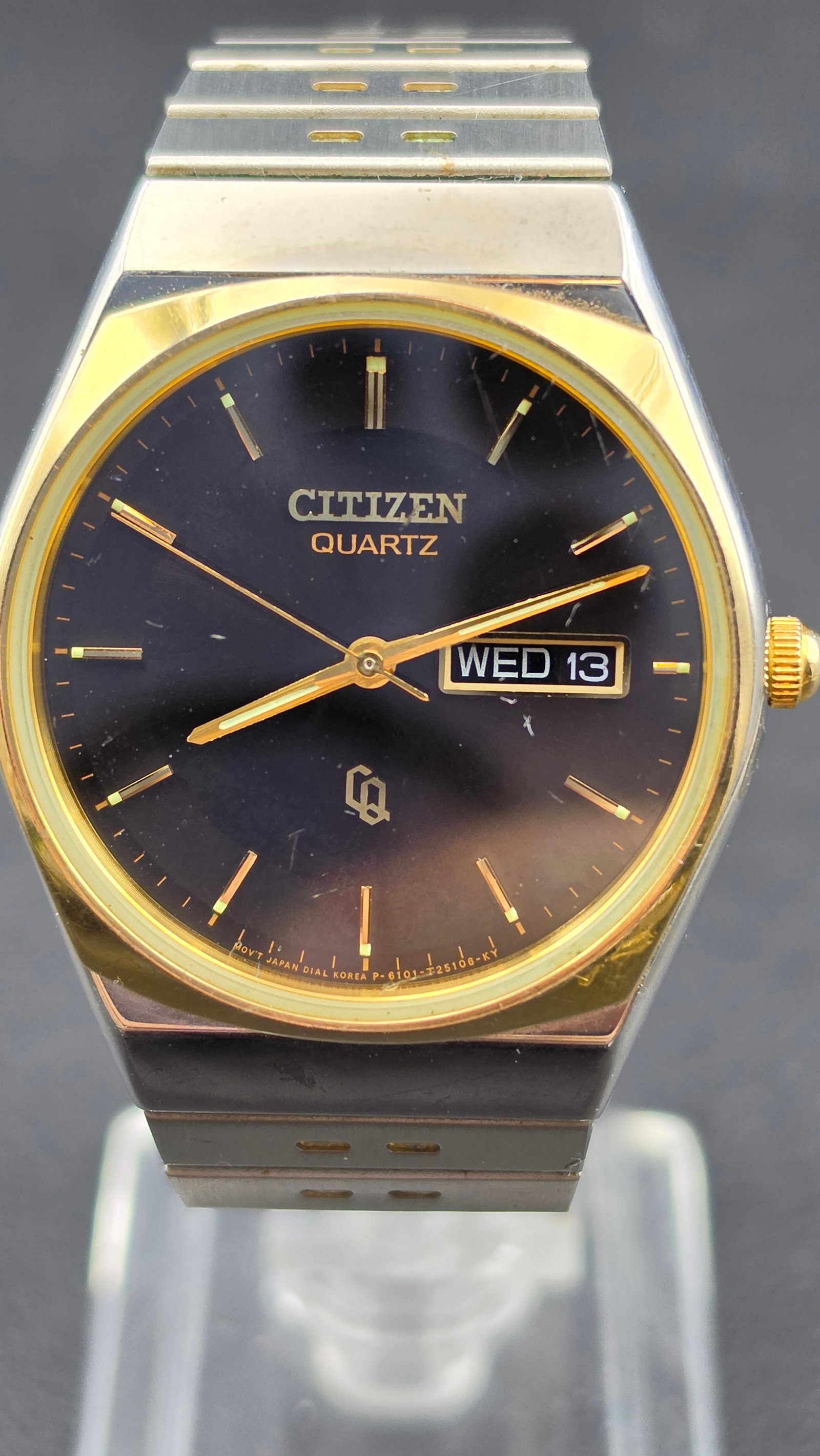 Citizen Quartz Day Date Black Dial Gold Tone Steel Bracelet Ref 6101 915119 Japan 1980s 34mm Running: Vintage Citizen quartz day-date wristwatch featuring a black dial with gold-tone baton indices and matching hands, day-date window at 3 showing WED 13, and Citizen “Q” logo above 6. Dial text 