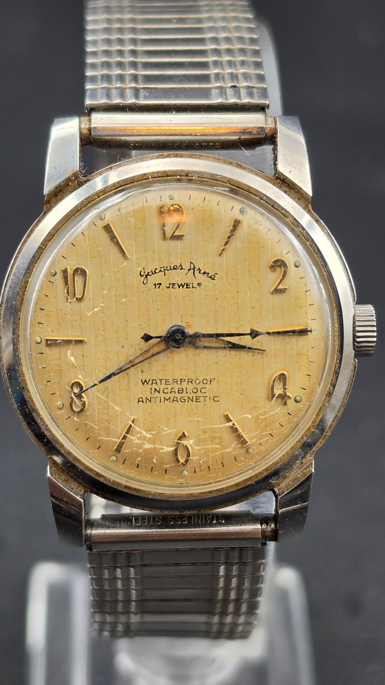 1950s Jacques Arne 17J Incabloc Waterproof Antimagnetic Swiss Dress Watch 33mm Running: Vintage Jacques Arne Swiss wristwatch featuring a textured champagne dial with applied Arabic numerals and dagger markers. Dial signed “17 Jewels” with Waterproof, Incabloc, Antimagnetic desig