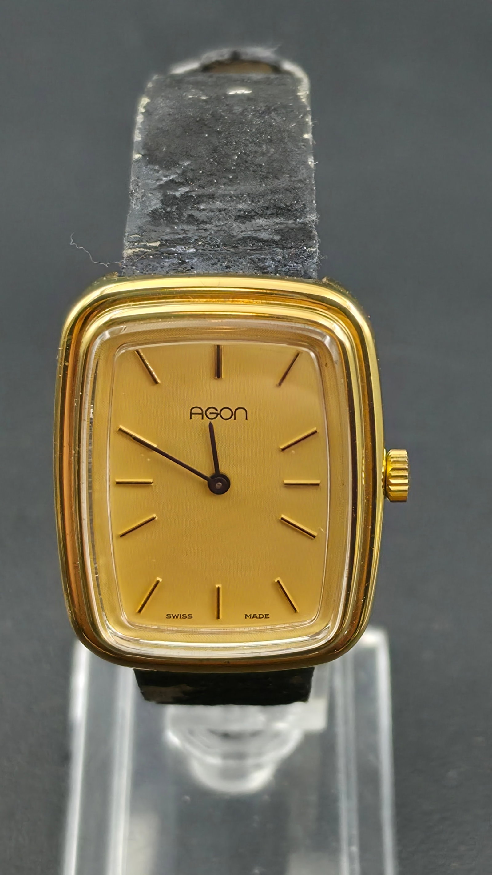 Vintage Agon Swiss Made Ladies Manual Wind Watch Gold-Tone Cushion Case Champagne Dial 29mm Runs: Up for auction is a vintage Agon Swiss Made ladies manual wind wristwatch. This sleek and elegant timepiece features a champagne gold-tone textured dial with slim baton hour markers and blued steel ha