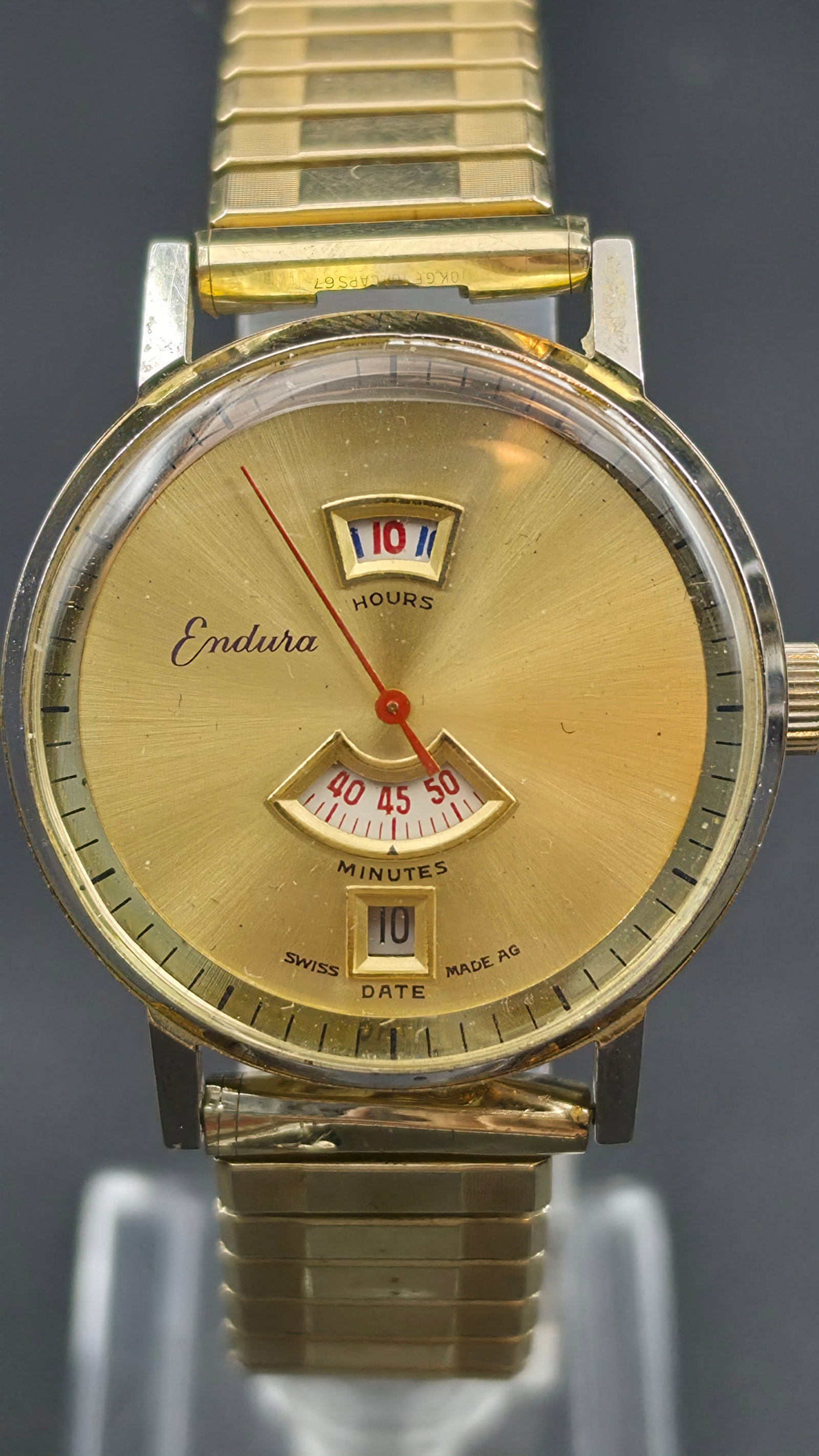 Endura Jump Hour Swiss Watch 34mm Agon Movement Ref 12103DR Gold Tone Runs: Vintage Endura manual wind jump hour wristwatch, Swiss Made AG. This is an unusual and collectible timepiece featuring a true jump hour display. The champagne gold sunburst dial reads Endura in script