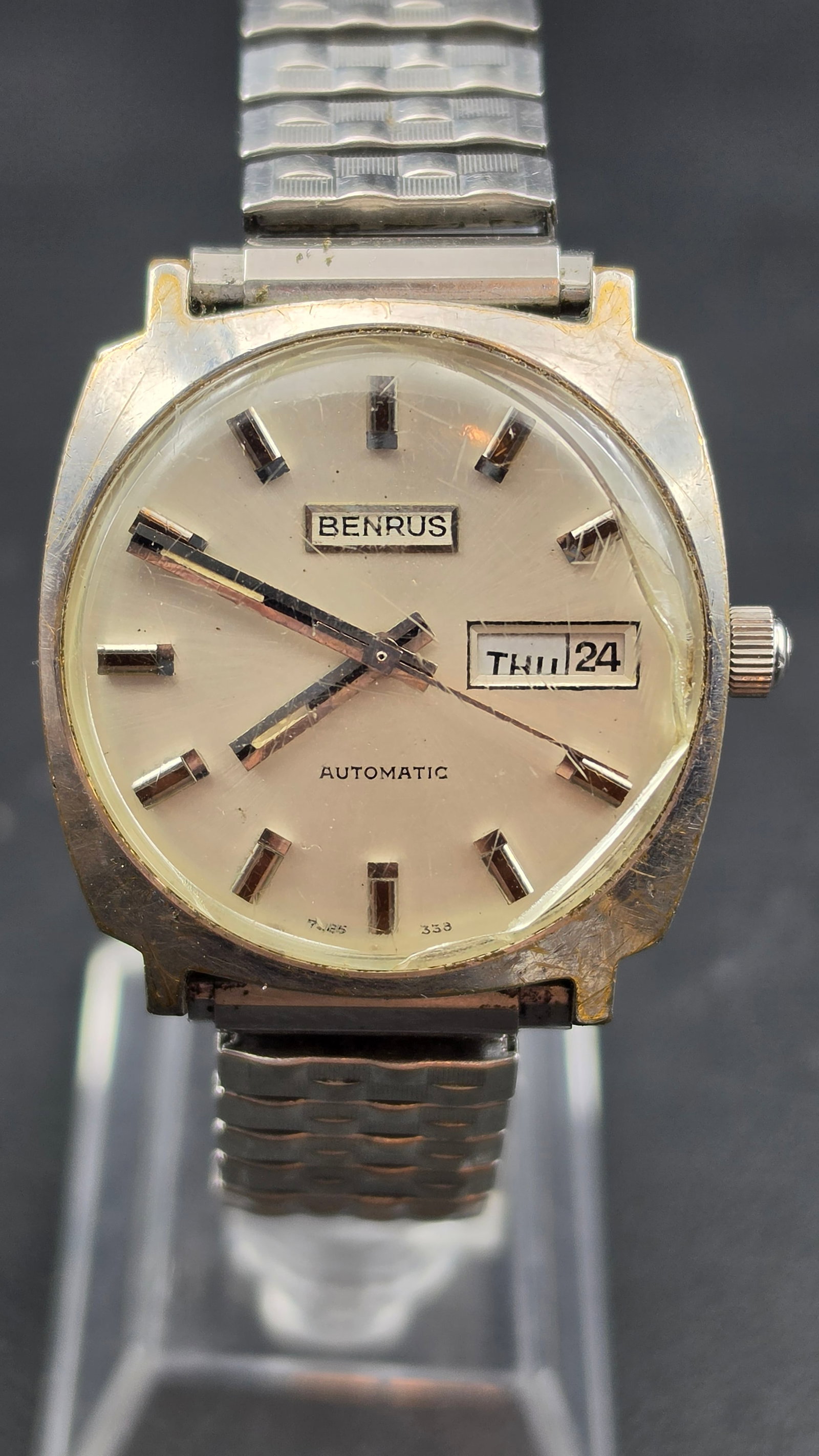 Benrus automatic mens watch base metal bezel stainless steel back day date open thru crystal 33mm: This is a vintage Benrus automatic self-winding mens wristwatch with day and date display. The cushion shaped case measures 33mm and is stamped on the case back Base Metal Bezel, Open Thru Crystal, St