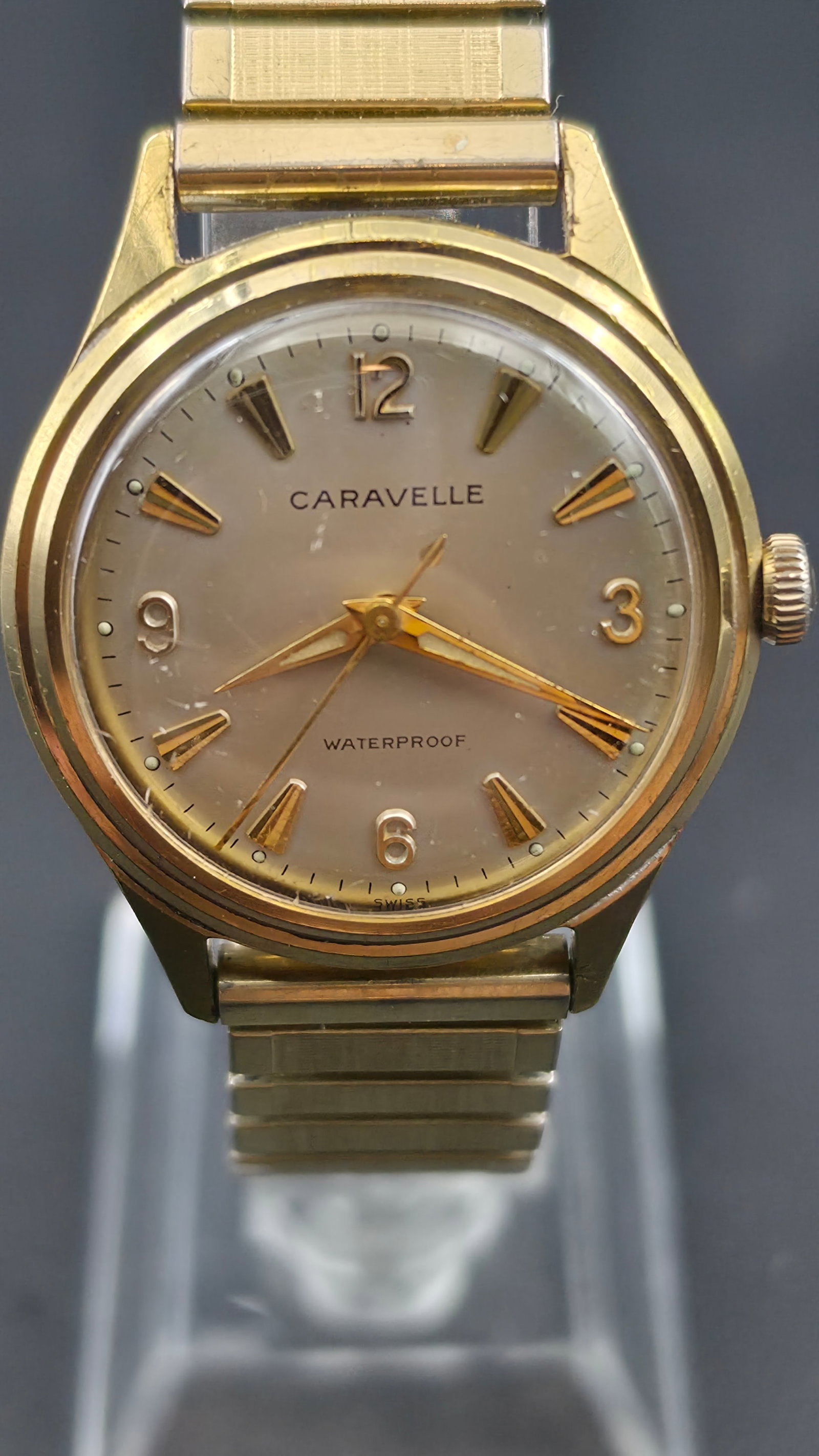 Vintage Caravelle Swiss 7 Jewel Mechanical Watch 32.35mm Waterproof: Champagne dial with Caravelle text, gold-tone applied dagger hour markers, Arabic numerals at 12, 3, 6, and 9, Waterproof text below center, and Swiss text at the bottom. Gold-tone dauphine hands. Rou