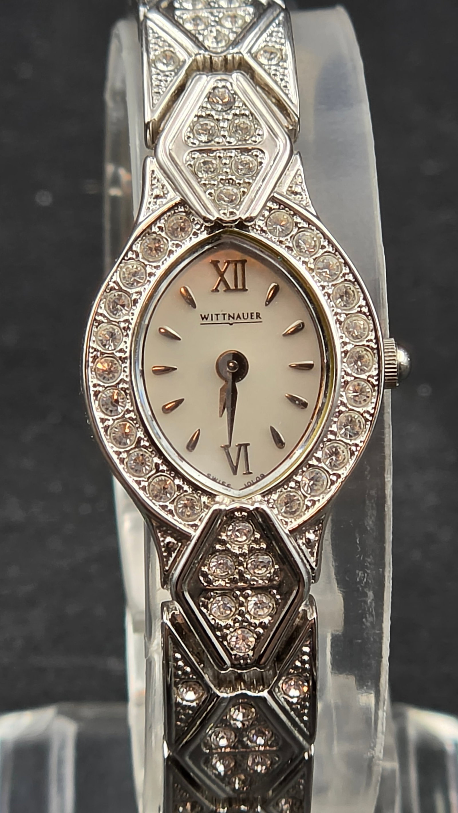 Wittnauer A4 Ladies Crystal Bracelet Watch 17.47mm Sapphire Crystal Stainless Steel Back C837313: White oval dial with Wittnauer text, Roman numerals at 12 and 6, applied gold-tone baton markers at all other positions, and Swiss Solar text at the bottom edge. Slim gold-tone hands. Small oval case 