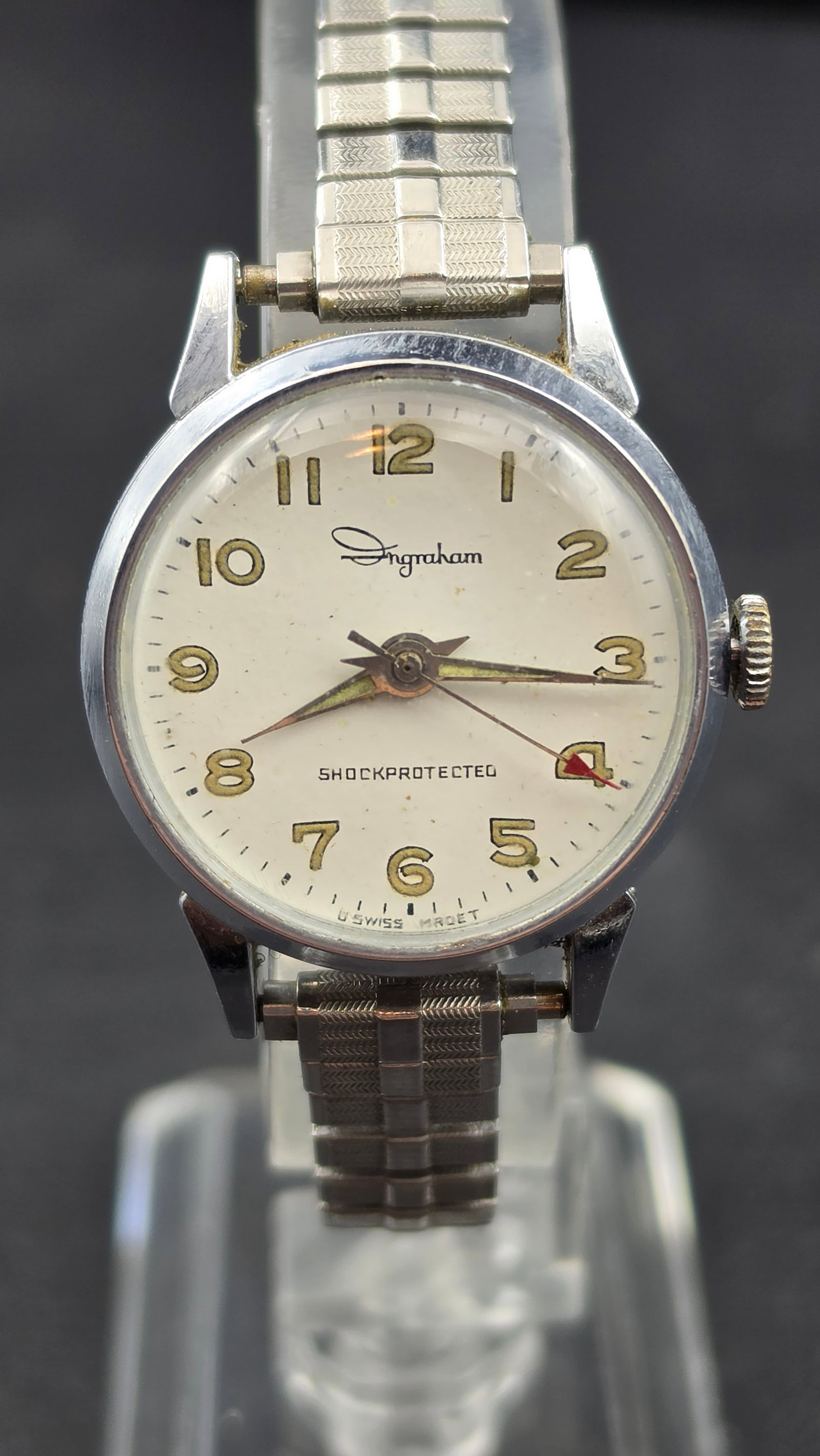 Ingraham Shockprotected Swiss Made Manual Wind Watch 28.86mm Base Metal Case: Vintage Ingraham manual wind wristwatch with a Swiss made base metal case measuring 28.86mm per digital calipers. The cream dial features full Arabic numerals 1 through 12 in gold tone, a minute track
