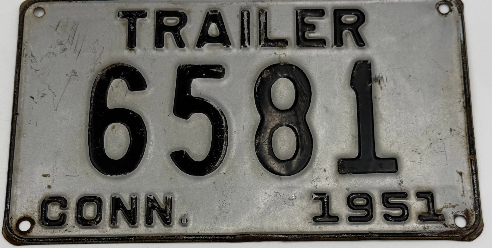 1951 Connecticut Trailer License Plate 6581: Original 1951 Connecticut Trailer license plate featuring number 6581. Embossed steel plate with silver and black finish, showing authentic vintage wear, scratches, rust, and patina consistent with ag
