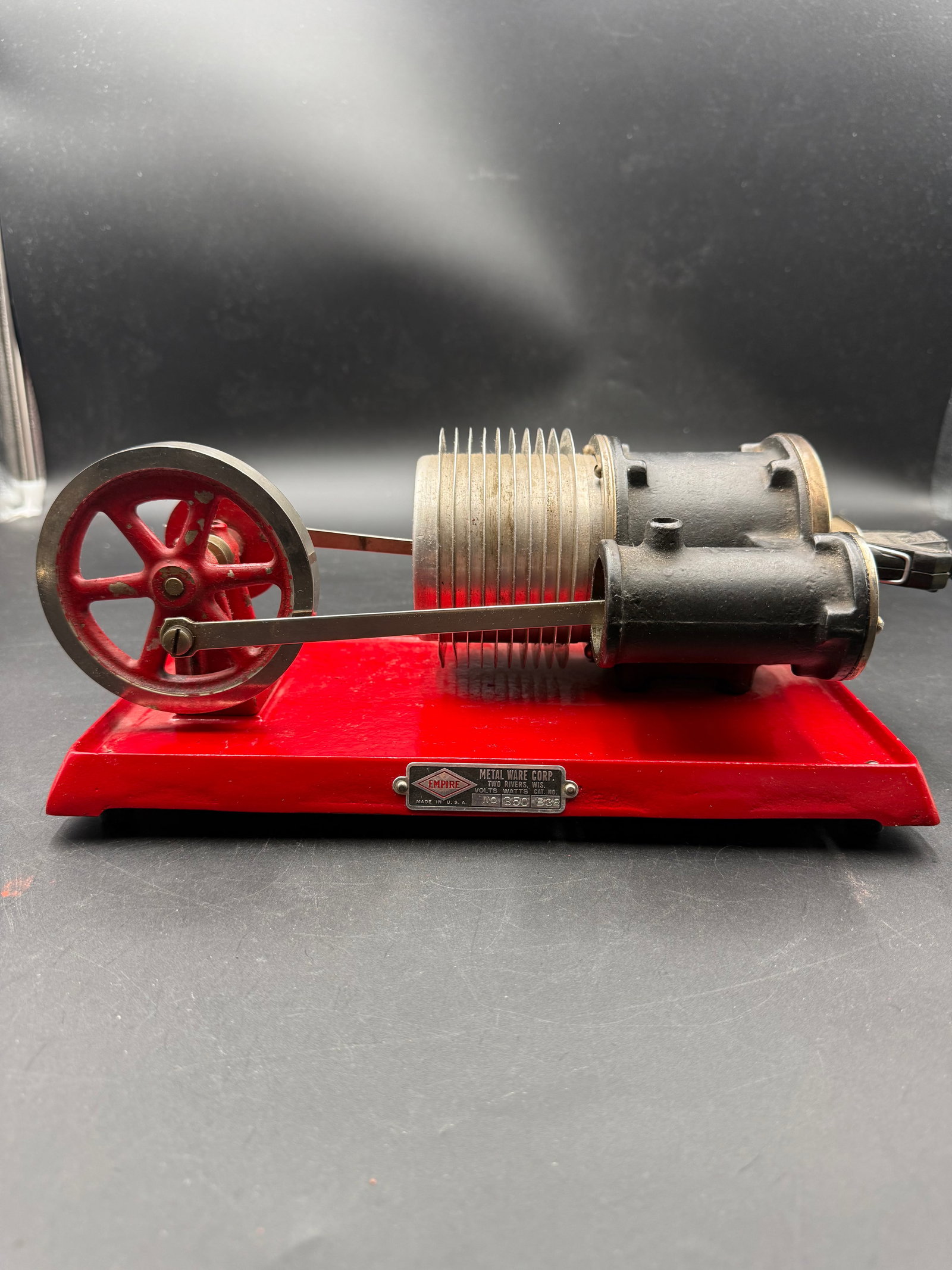 Empire B38 Hot Air Engine: Empire B38 Hot Air Engine, manufactured by Metal Ware Corp circa the 1930s. It features an electric heating element and operates using heat to drive a piston and flywheel. The engine has a red base wi