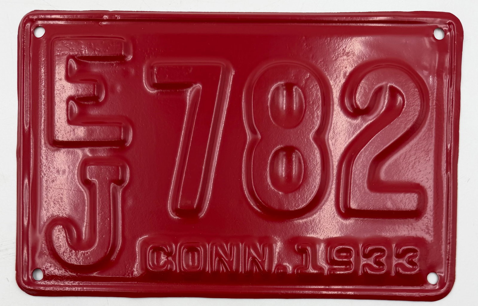 1933 Connecticut License Plate EJ-782: Original 1933 Connecticut license plate featuring number EJ-782. Embossed steel plate with red finish and matching embossed characters, showing a clean restored or repainted appearance with light wear