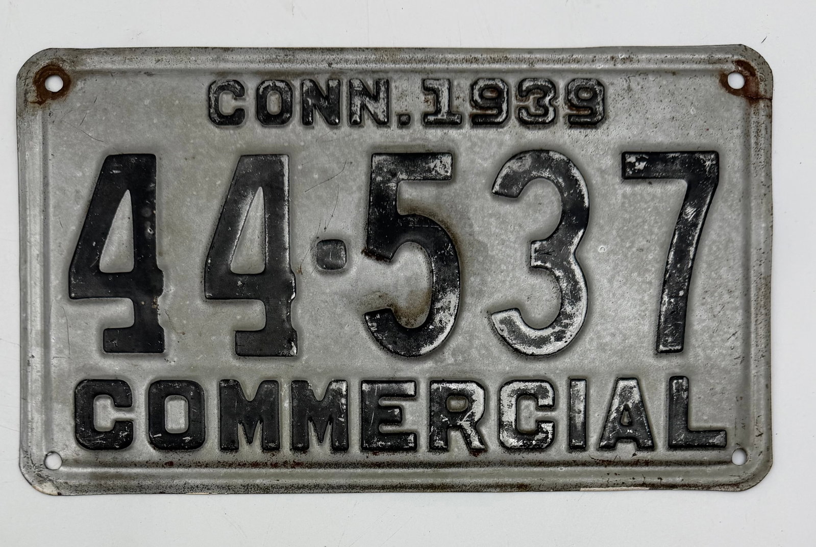 1939 Connecticut Commercial License Plate 44-537: Original 1939 Connecticut commercial vehicle license plate with embossed black numbers on silver background. Features “COMMERCIAL” designation and number 44-537. Authentic vintage steel plate 