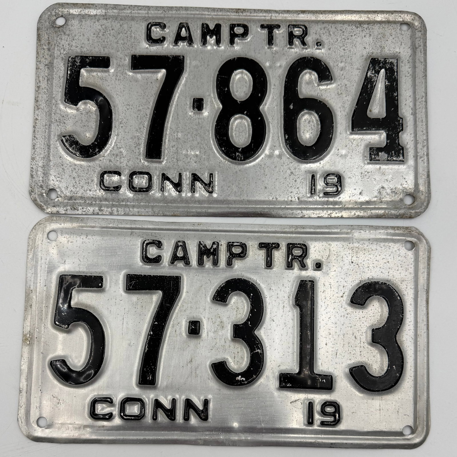 1957 Connecticut Camp Trailer License Plate Pair: Matching pair of original 1957 Connecticut Camp Trailer license plates featuring embossed black lettering on aluminum bases. Includes numbers 57-864 and 57-313 marked “CAMPTR.” and “CONN.&rd