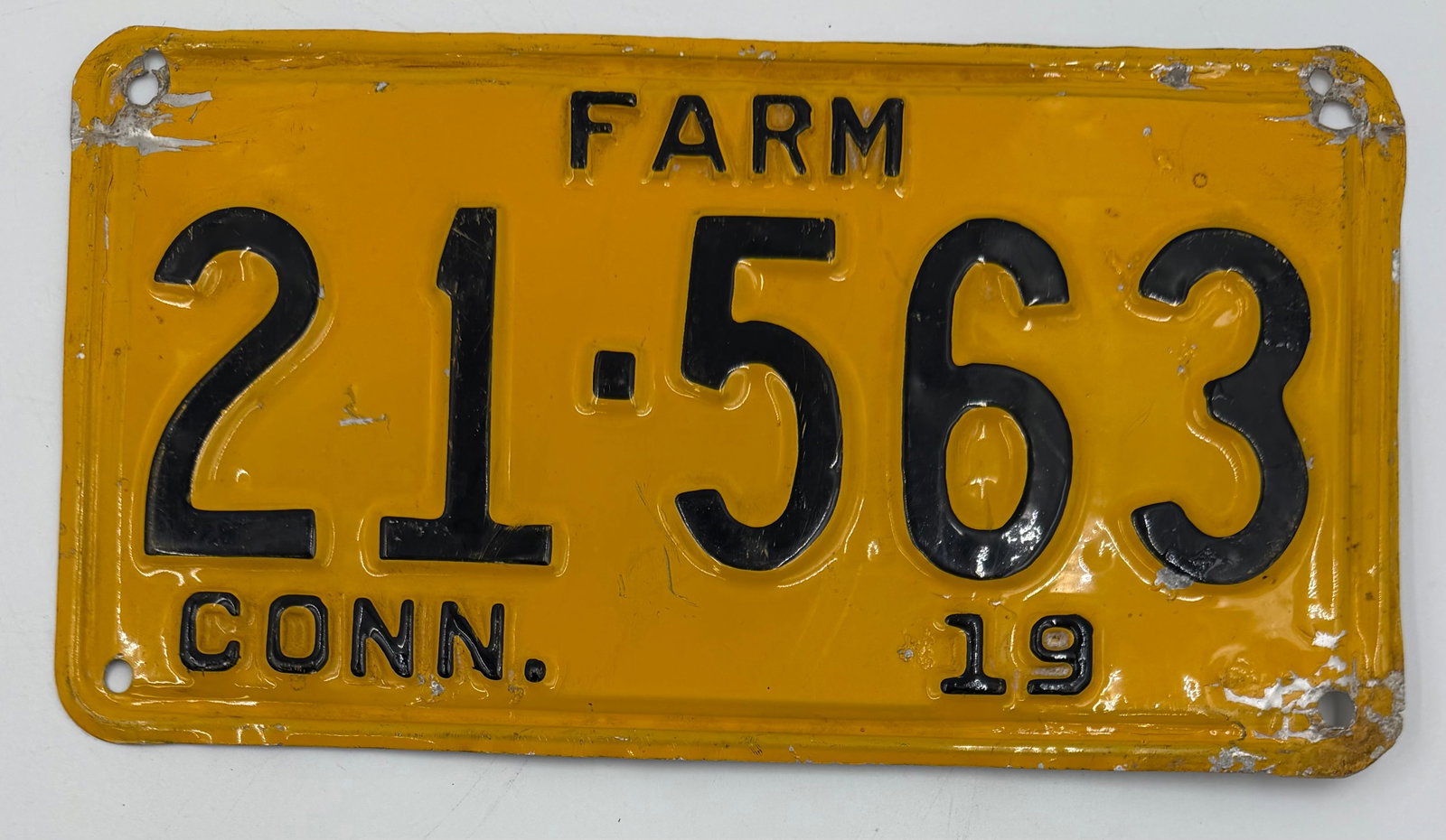 1940 Connecticut Farm License Plate 21-563: Original 1940 Connecticut FARM license plate, number 21-563, featuring yellow background with black embossed lettering. Vintage steel plate with visible wear, paint loss, extra mounting holes, and age