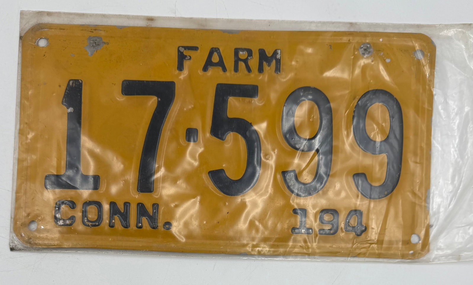 1940 Connecticut Farm License Plate 21-563: Original 1940 Connecticut FARM license plate, number 21-563, featuring yellow background with black embossed lettering. Vintage steel plate with visible wear, paint loss, extra mounting holes, and age