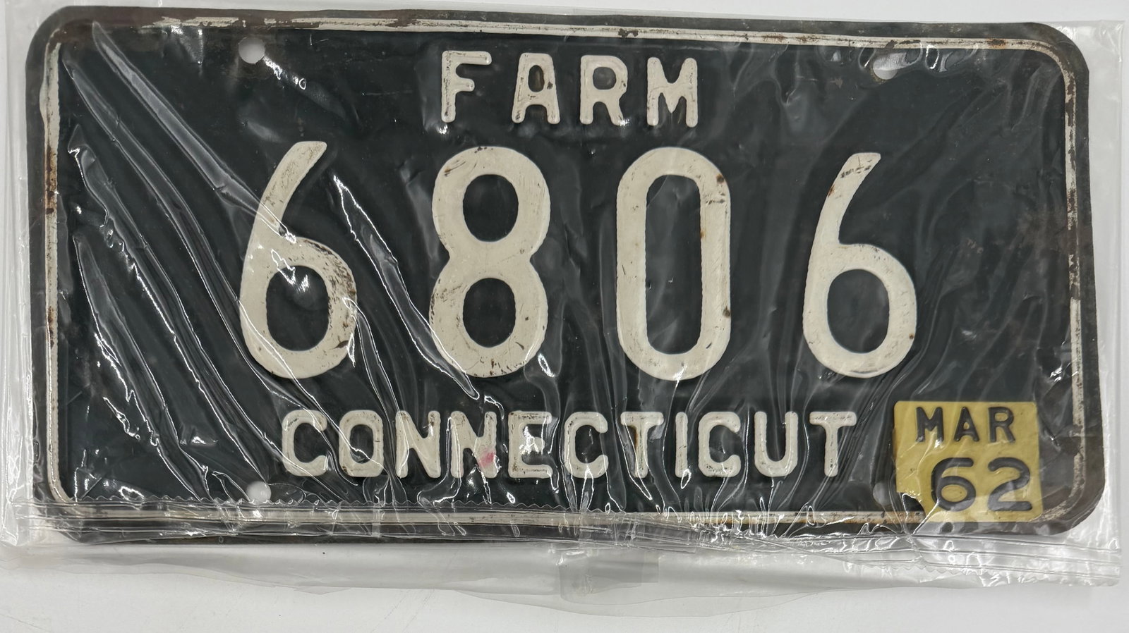 1962 Connecticut Farm License Plate 6806: Original 1962 Connecticut FARM license plate, number 6806, featuring black background with white embossed lettering and March 1962 validation tab. Comes in protective sleeve. Shows light wear, surface