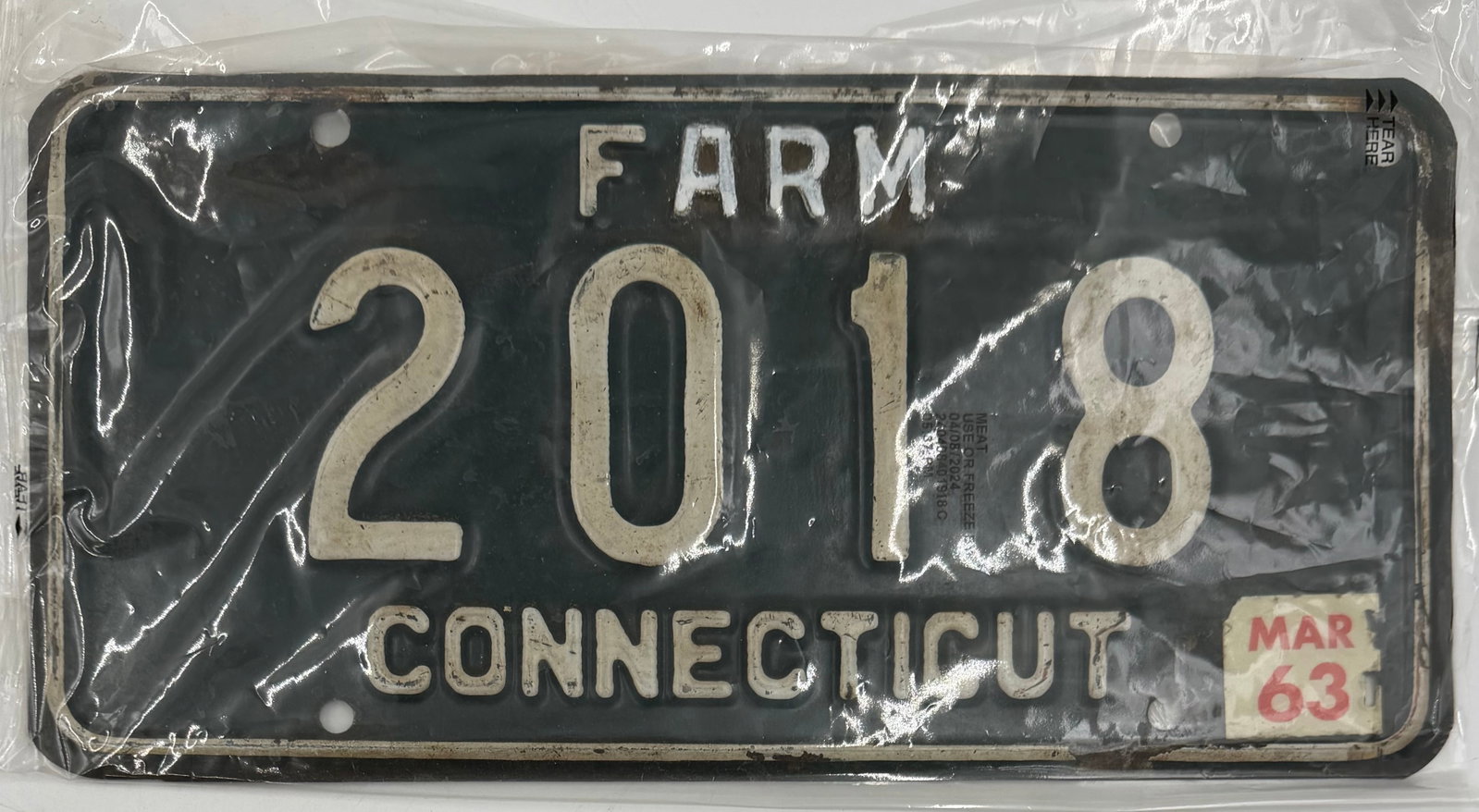 1963 Connecticut Farm License Plate 2018: Original 1963 Connecticut FARM license plate, number 2018, with black background and white embossed lettering. Includes March 1963 validation sticker and protective sleeve. Shows authentic vintage wea