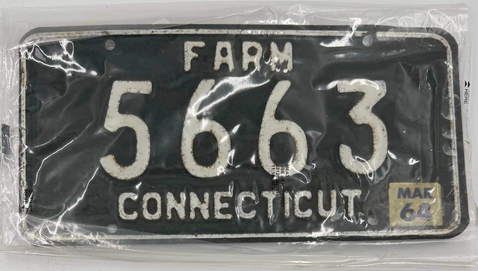 1964 Connecticut Farm License Plate 5663: Original 1964 Connecticut FARM license plate, number 5663, featuring black background with white embossed lettering and March 1964 validation tab. Stored in protective sleeve. Shows normal vintage wea