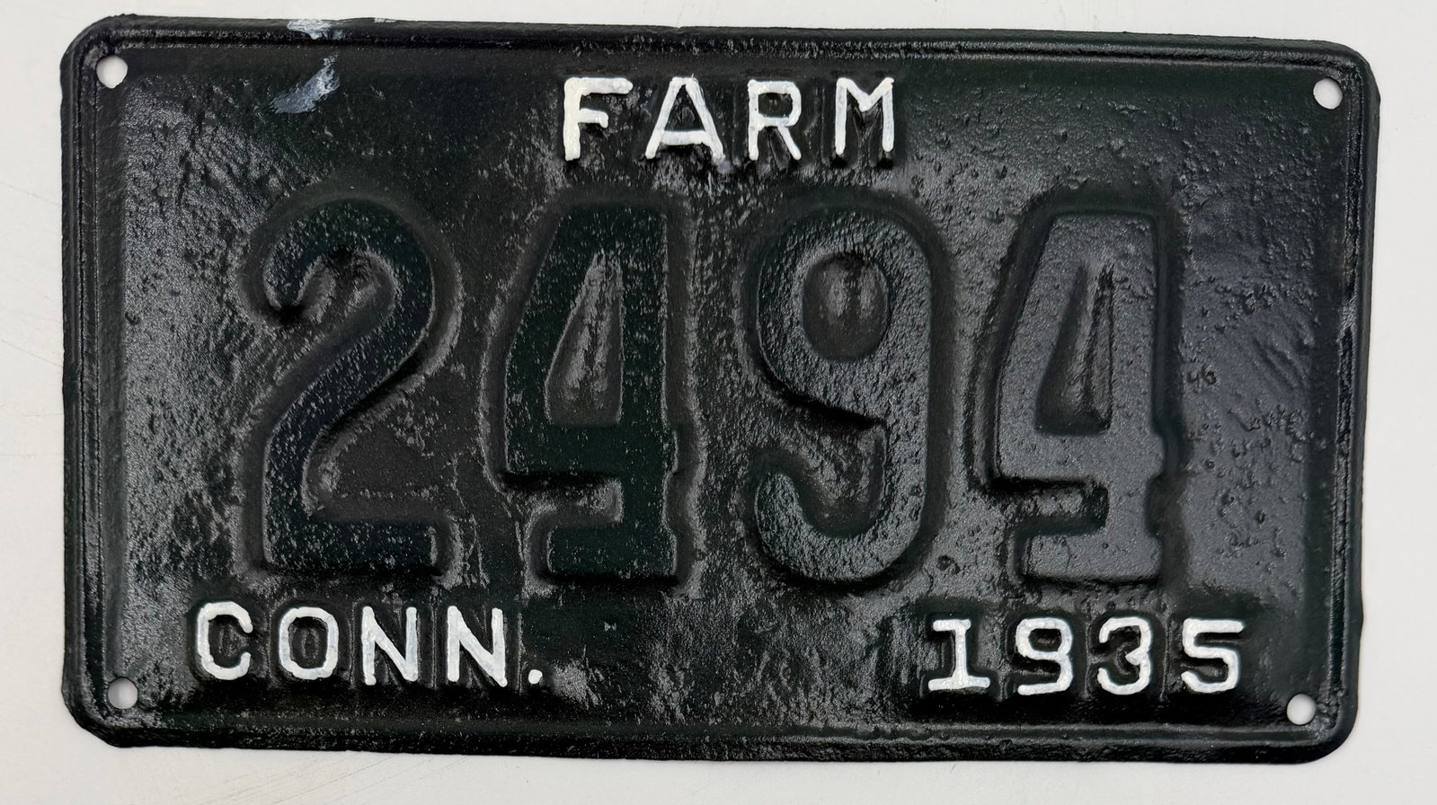 1935 Connecticut Farm License Plate 2494: Original 1935 Connecticut FARM license plate featuring embossed numbers and lettering with black background and white paint details. Vintage plate shows age, repainting, and rustic wear that adds to i