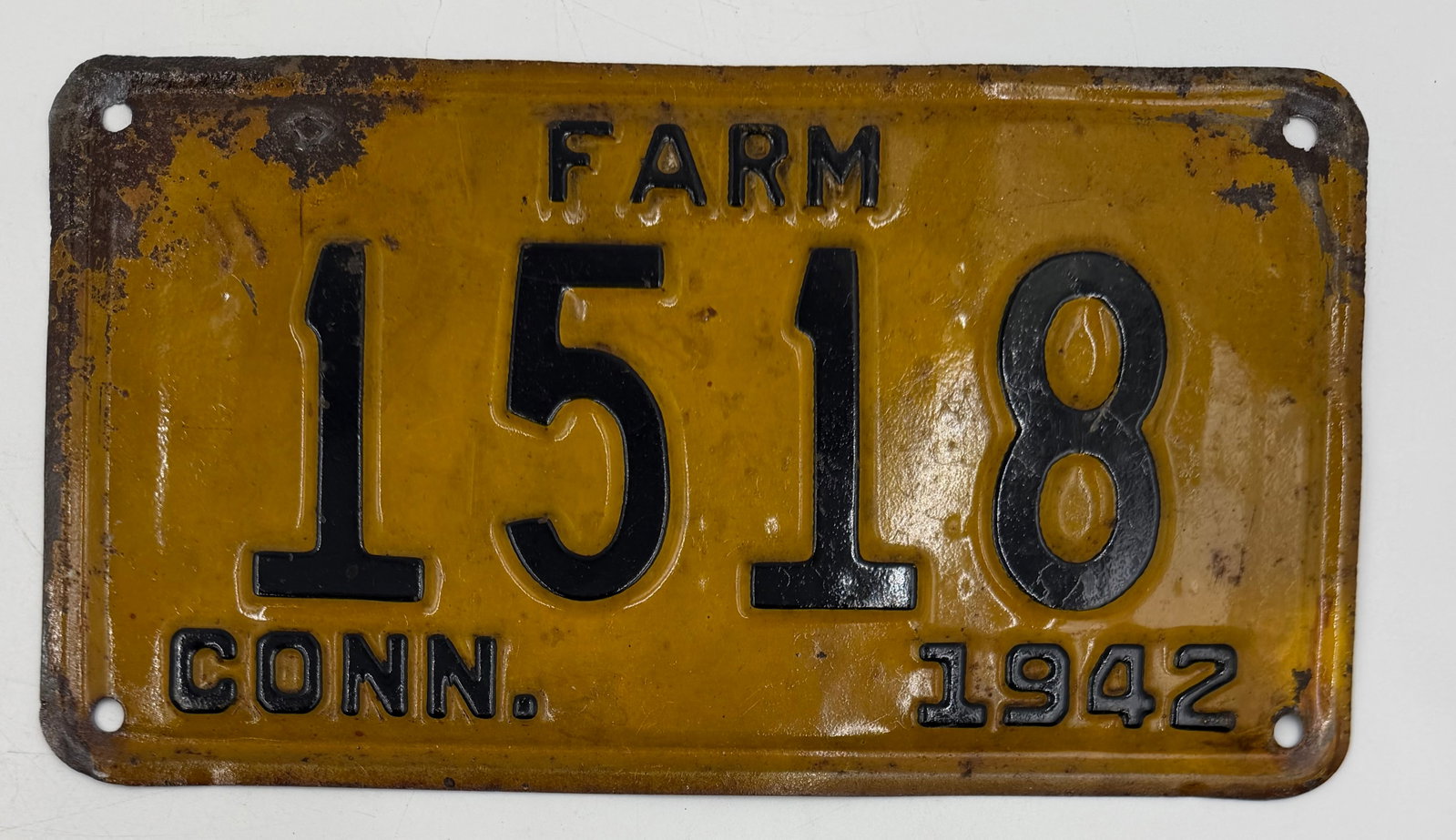 1942 Connecticut Farm License Plate 1518: Original 1942 Connecticut FARM license plate featuring embossed black numbers on yellow/orange background. Vintage plate shows authentic age wear, rust patina, and surface imperfections consistent wit