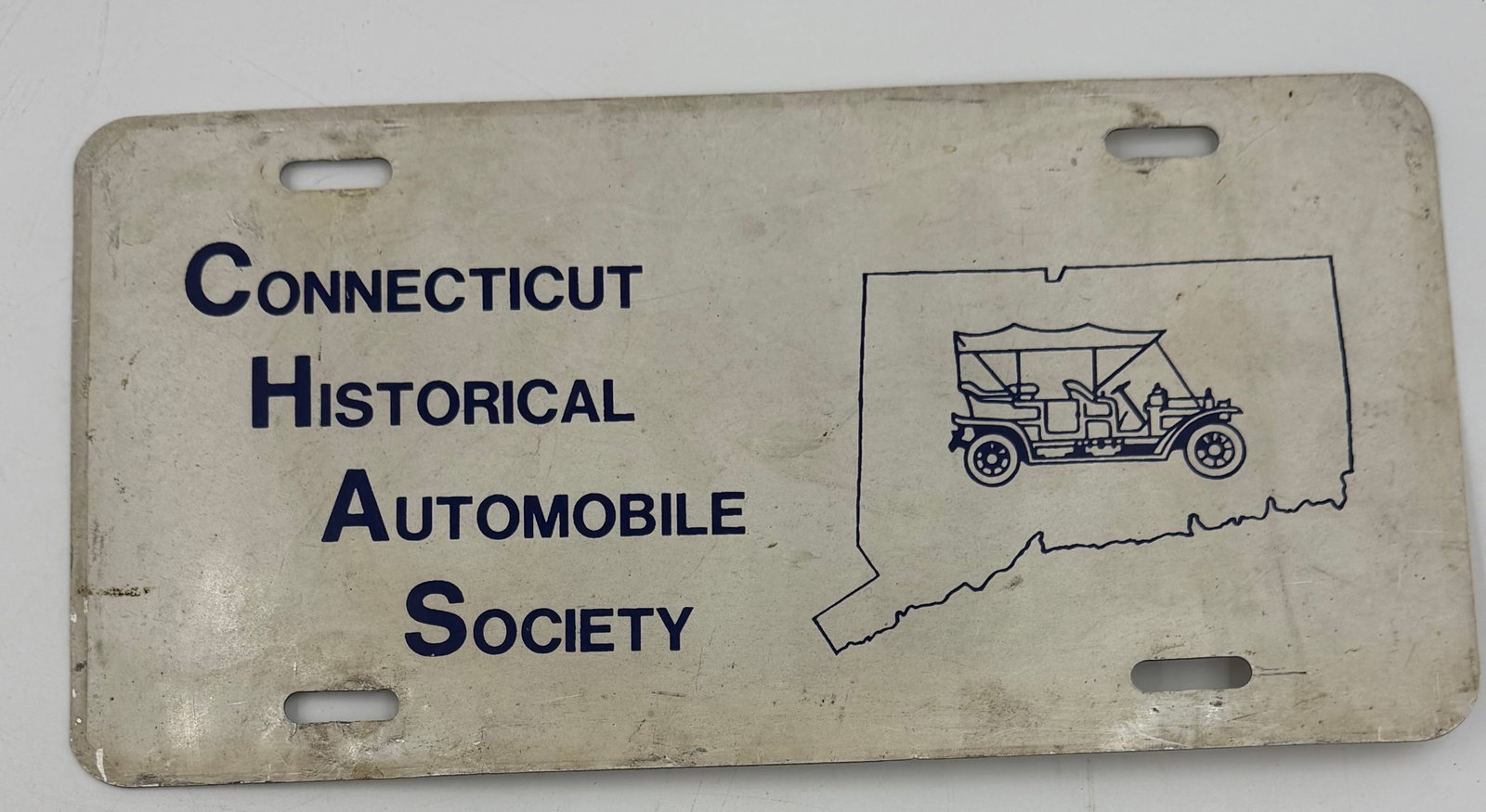 Vintage Connecticut Historical Automobile Society License Plate Sign: Vintage Connecticut Historical Automobile Society metal license plate/sign featuring blue lettering and antique automobile graphic inside the outline of Connecticut. Lightweight metal display piece wi