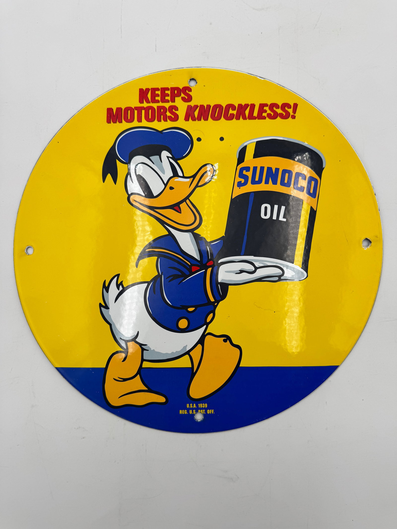 Vintage Sunoco Donald Duck Porcelain Gas Oil Sign: Vintage-style Sunoco Oil advertising sign featuring Donald Duck with slogan “Keeps Motors Knockless!” Marked U.S.A. 1939 Reg. U.S. Pat. Off. Bright yellow and blue colors with great garage, ga