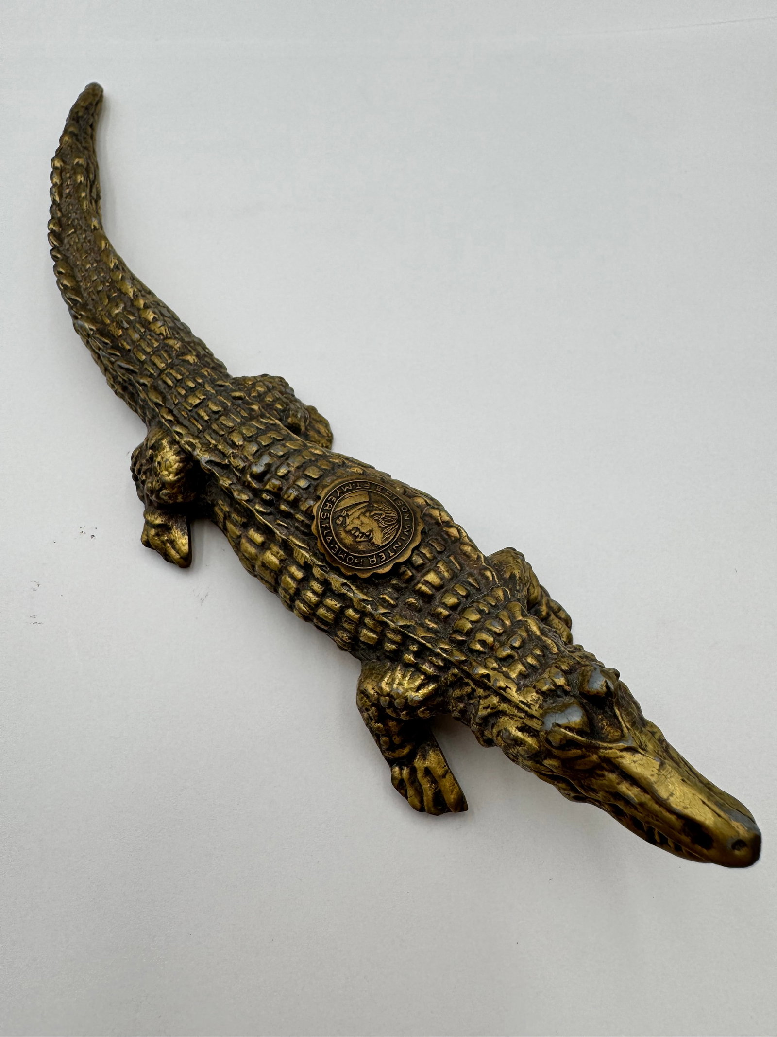 Vintage Cast Iron Brass Tone Alligator Figural F.T. Myers Florida Winter Home Souvenir: Vintage figural alligator souvenir featuring a raised medallion marked:“Edison Winter Home Ft. Myers Fla.”This decorative piece appears to be a mid-century Florida tourist souvenir inspired by