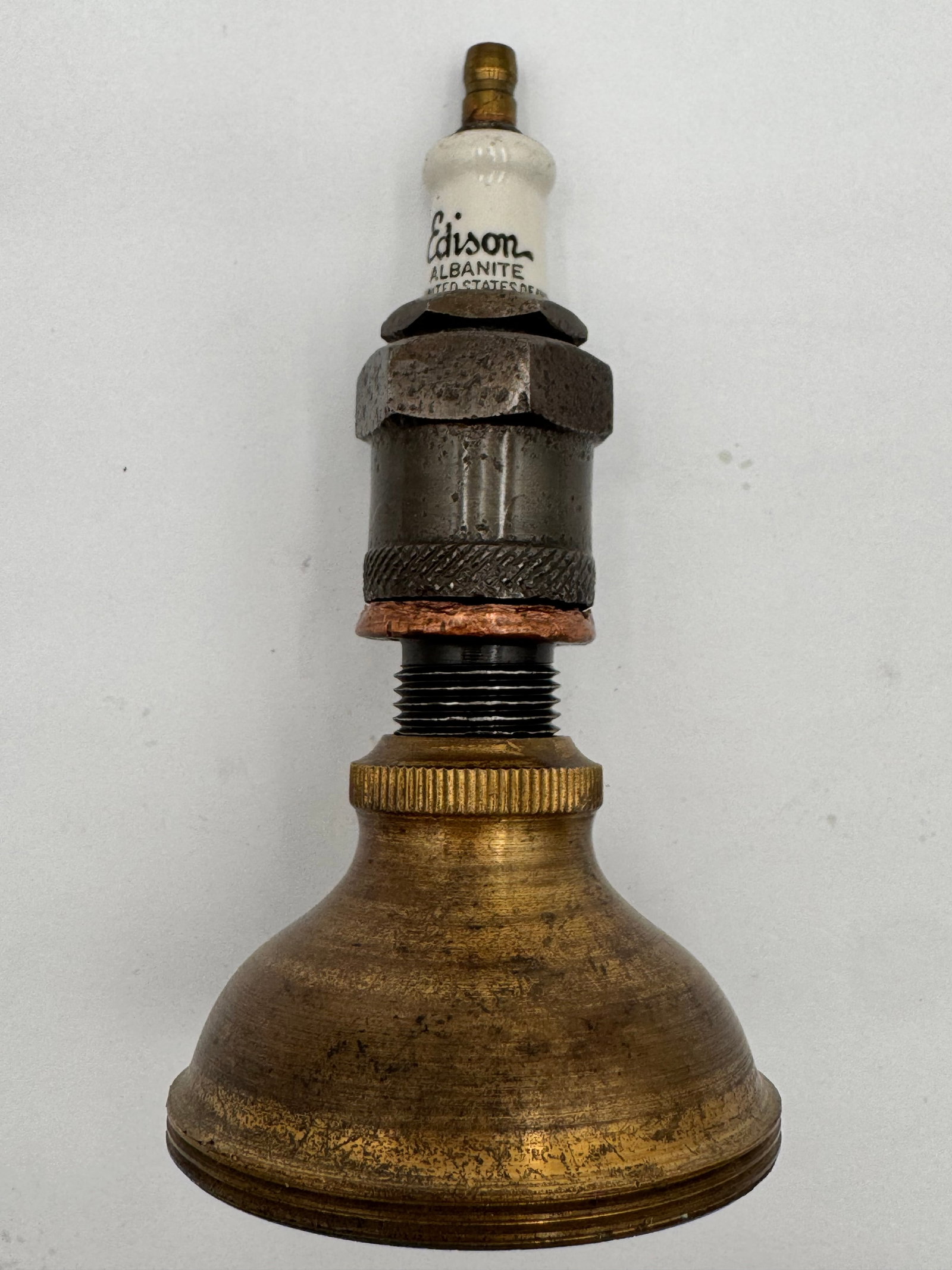 Antique Edison Albanite Spark Plug Brass Display Salesman Sample Automobilia: Antique Edison Albanite spark plug mounted on a brass horn-shaped base/display. Features original porcelain Edison Albanite spark plug marked “United States.”An unusual early automobilia or ig